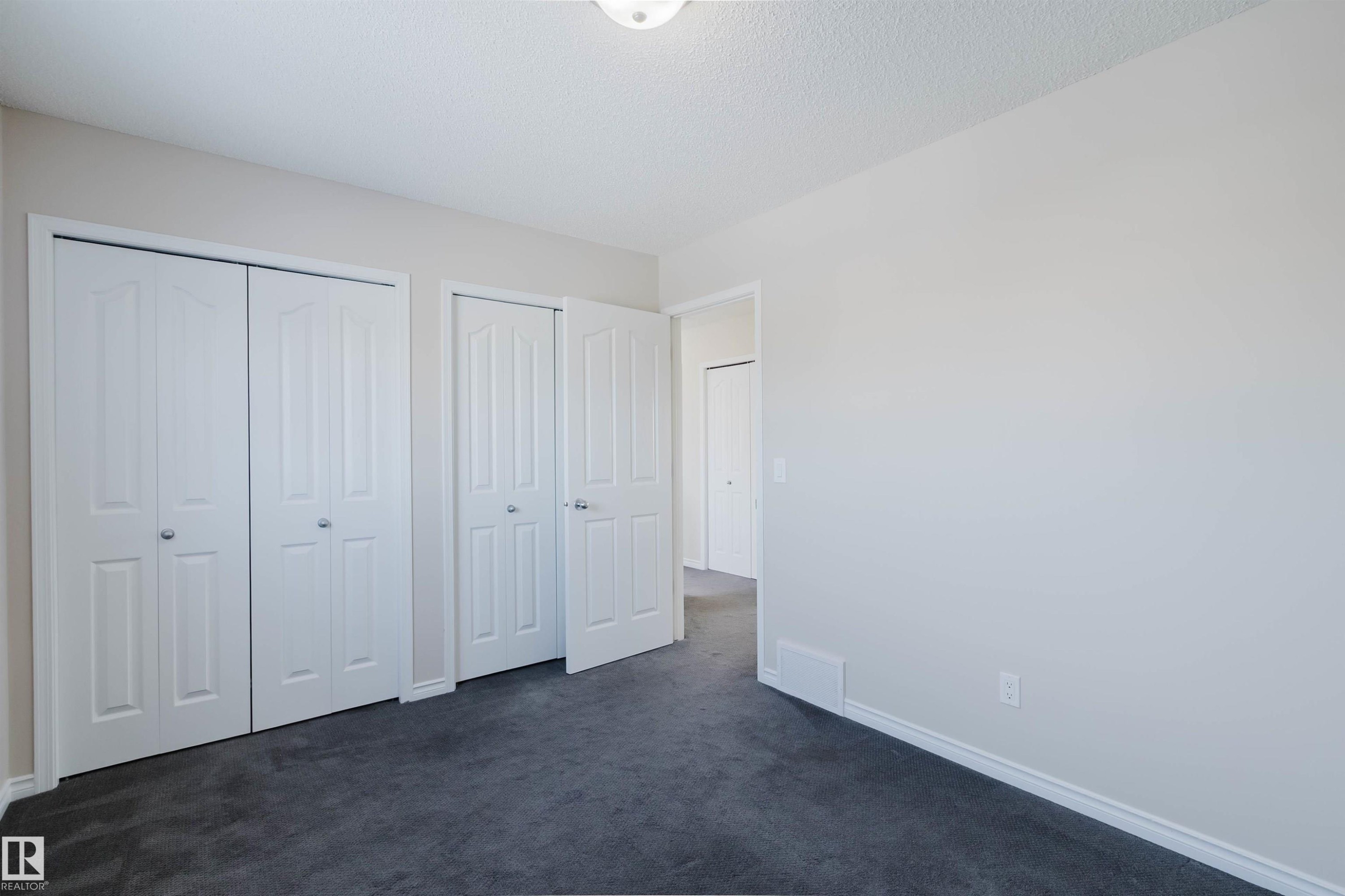 This room features neutral-toned walls, dark carpeting, and white bi-fold closet doors - 1135 112 Street, Edmonton, AB - Indoor
