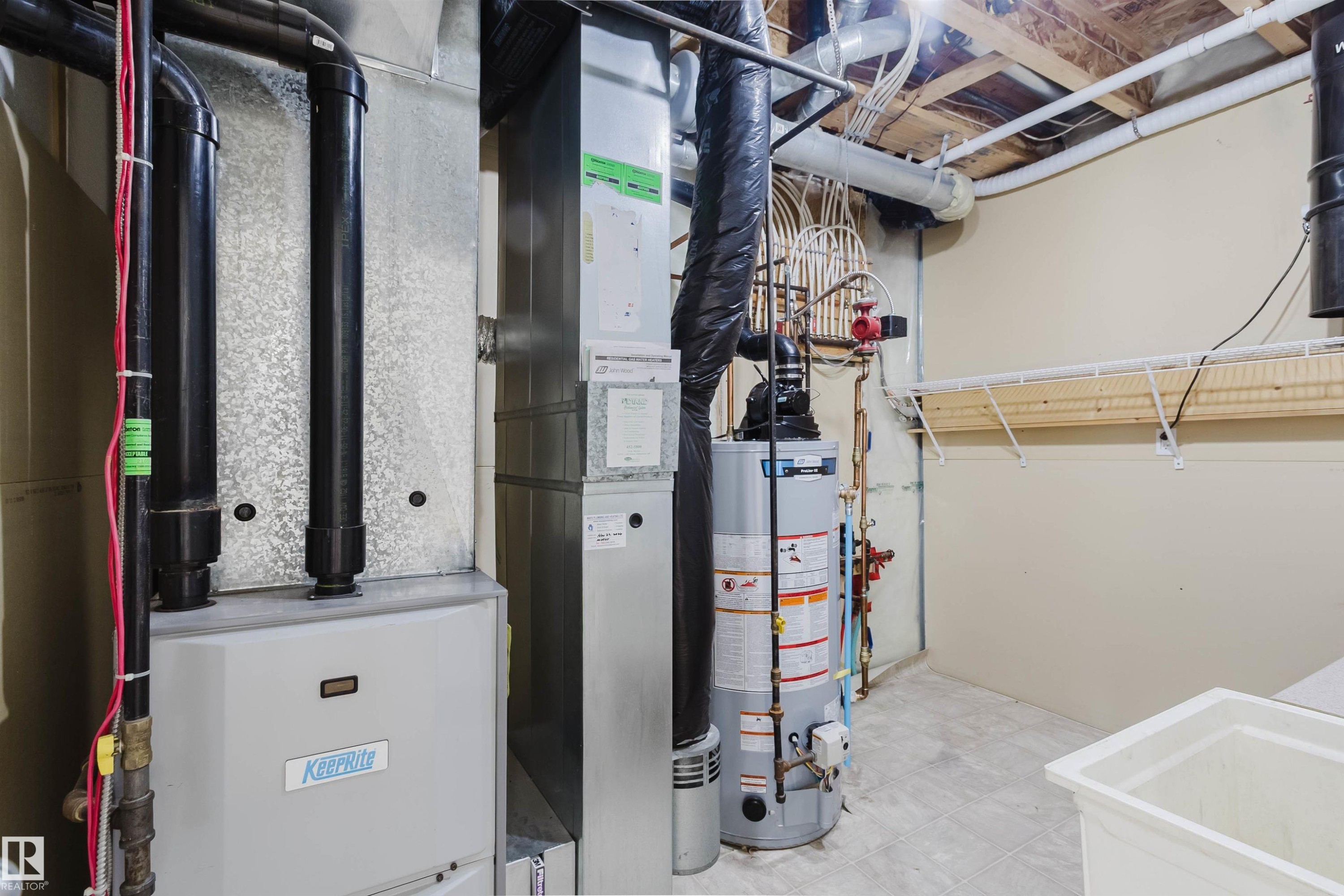 The property features a utility area with mechanical systems, including a water heater and furnace, along with a utility sink and wall-mounted shelving - 1135 112 Street, Edmonton, AB - Indoor
