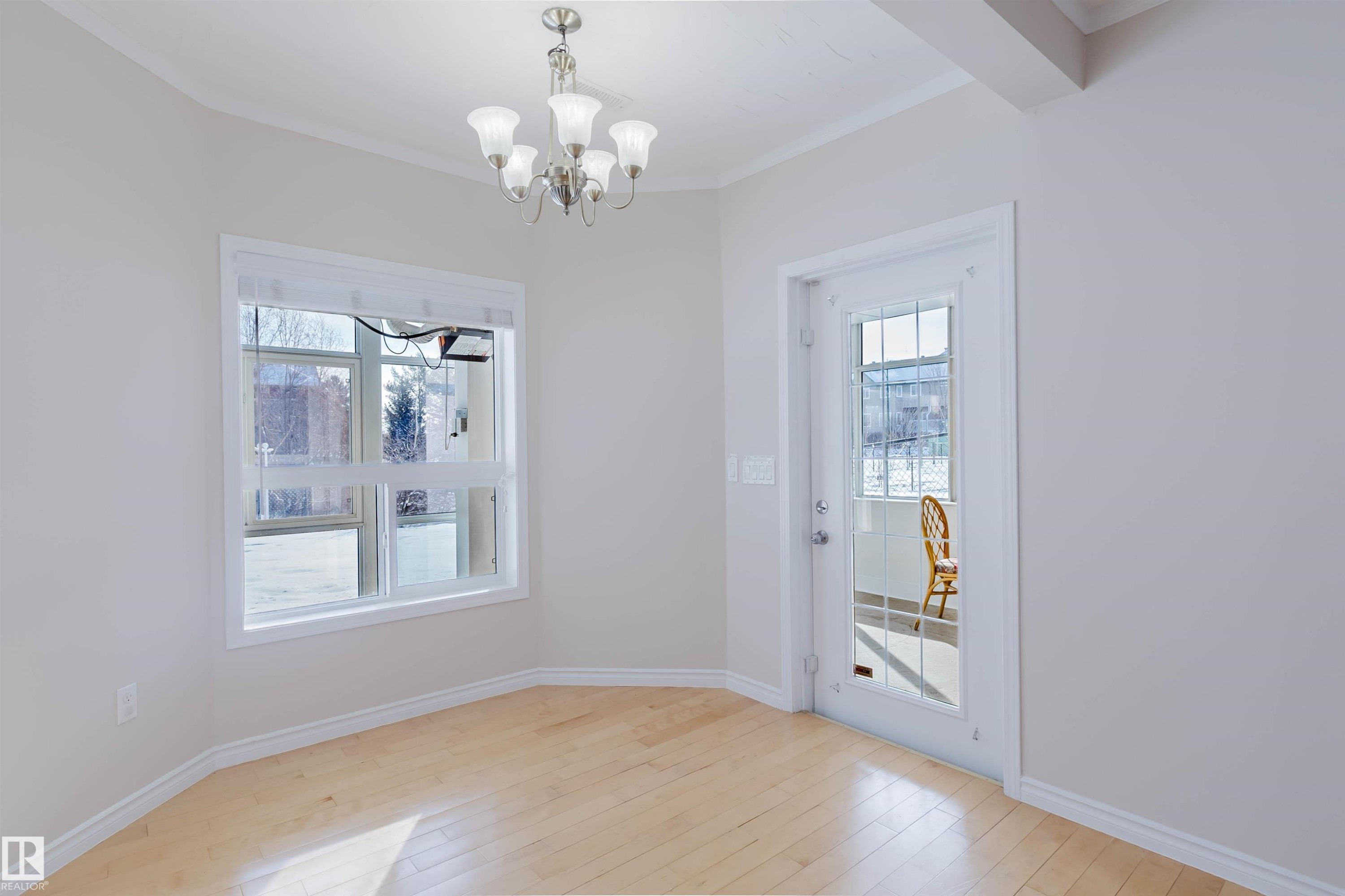 This bright room features light-toned hardwood flooring, a large window, and a glass-paneled door - 1135 112 Street, Edmonton, AB - Indoor Photo Showing Other Room