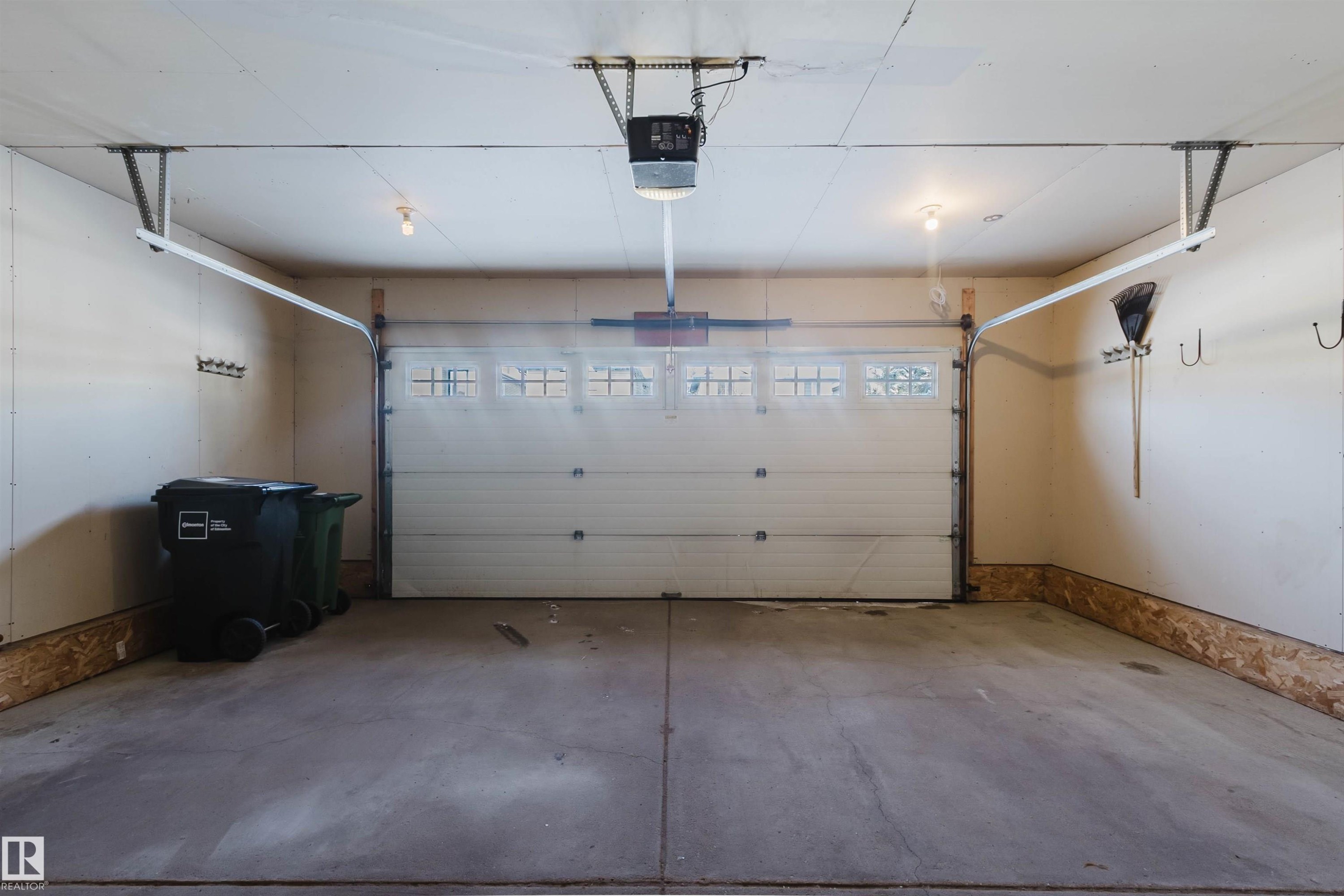 The property features a garage with a concrete floor, an overhead door with window panels, and interior lighting - 1135 112 Street, Edmonton, AB - Indoor Photo Showing Garage