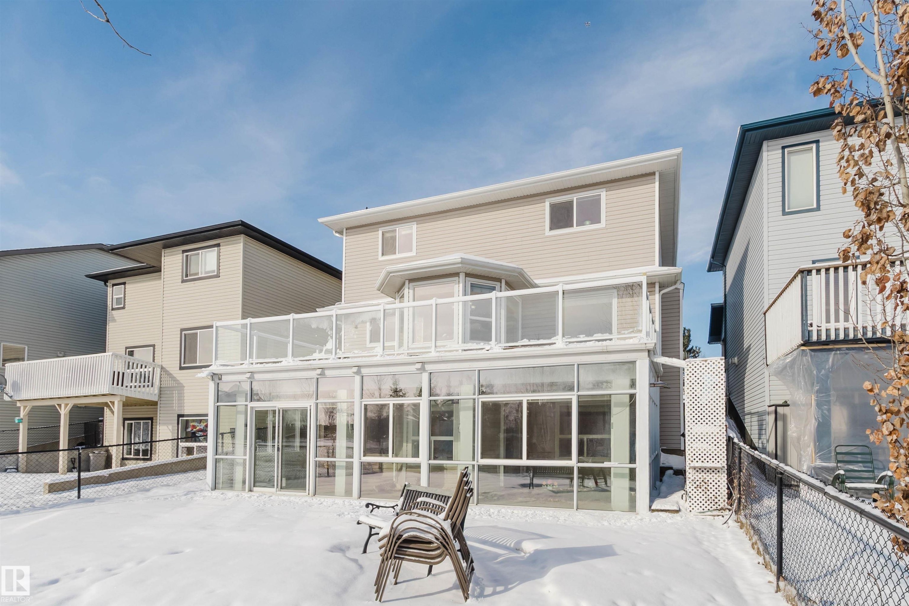 The property features a sunroom with large windows and a glass railing balcony above - 1135 112 Street, Edmonton, AB - Outdoor