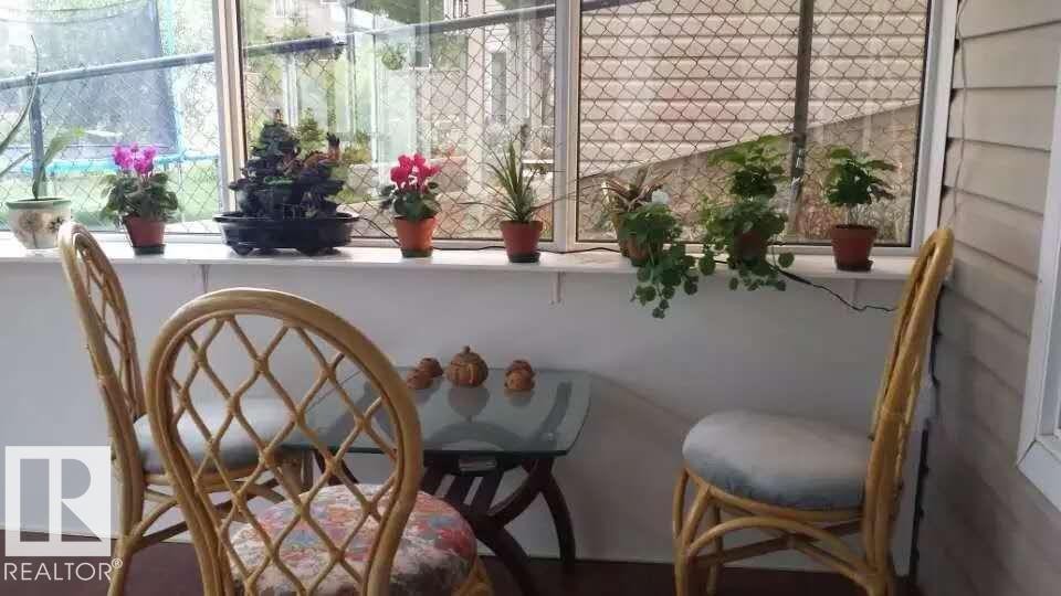 The property features a sunroom with large windows, a glass-top table, and rattan chairs - 1135 112 Street, Edmonton, AB - Indoor Photo Showing Other Room