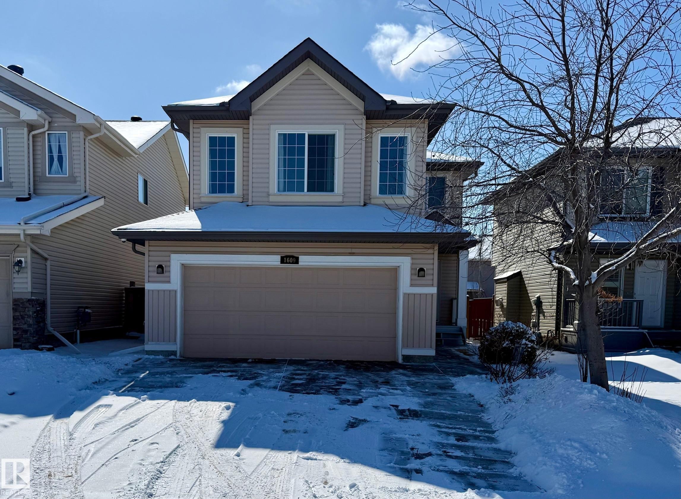 The property features an attached garage with a paved driveway - 1609 Hodgson Crest, Edmonton, AB - Outdoor