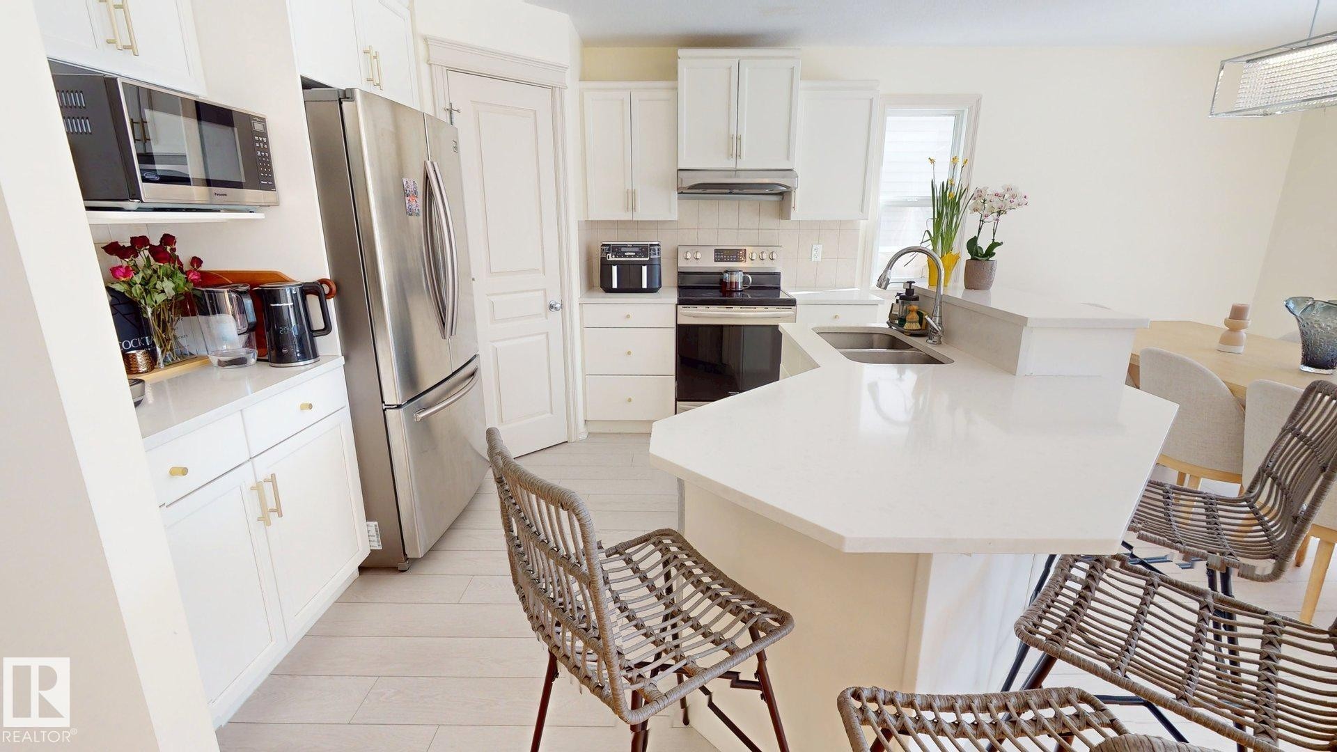The kitchen features white cabinetry, stainless steel appliances, and a light-colored countertop with an integrated sink - 1609 Hodgson Crest, Edmonton, AB - Indoor Photo Showing Kitchen With Double Sink With Upgraded Kitchen