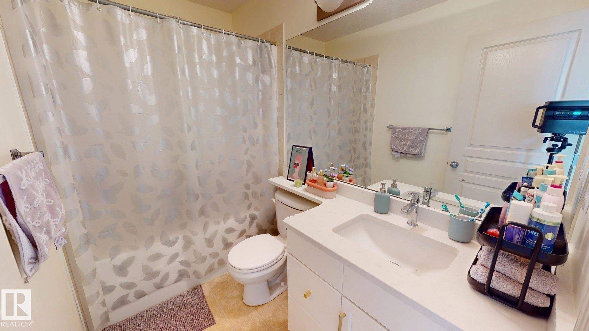 The bathroom features a vanity with a white countertop and an integrated sink, a toilet, and a shower with a shower curtain - 1609 Hodgson Crest, Edmonton, AB - Indoor Photo Showing Bathroom
