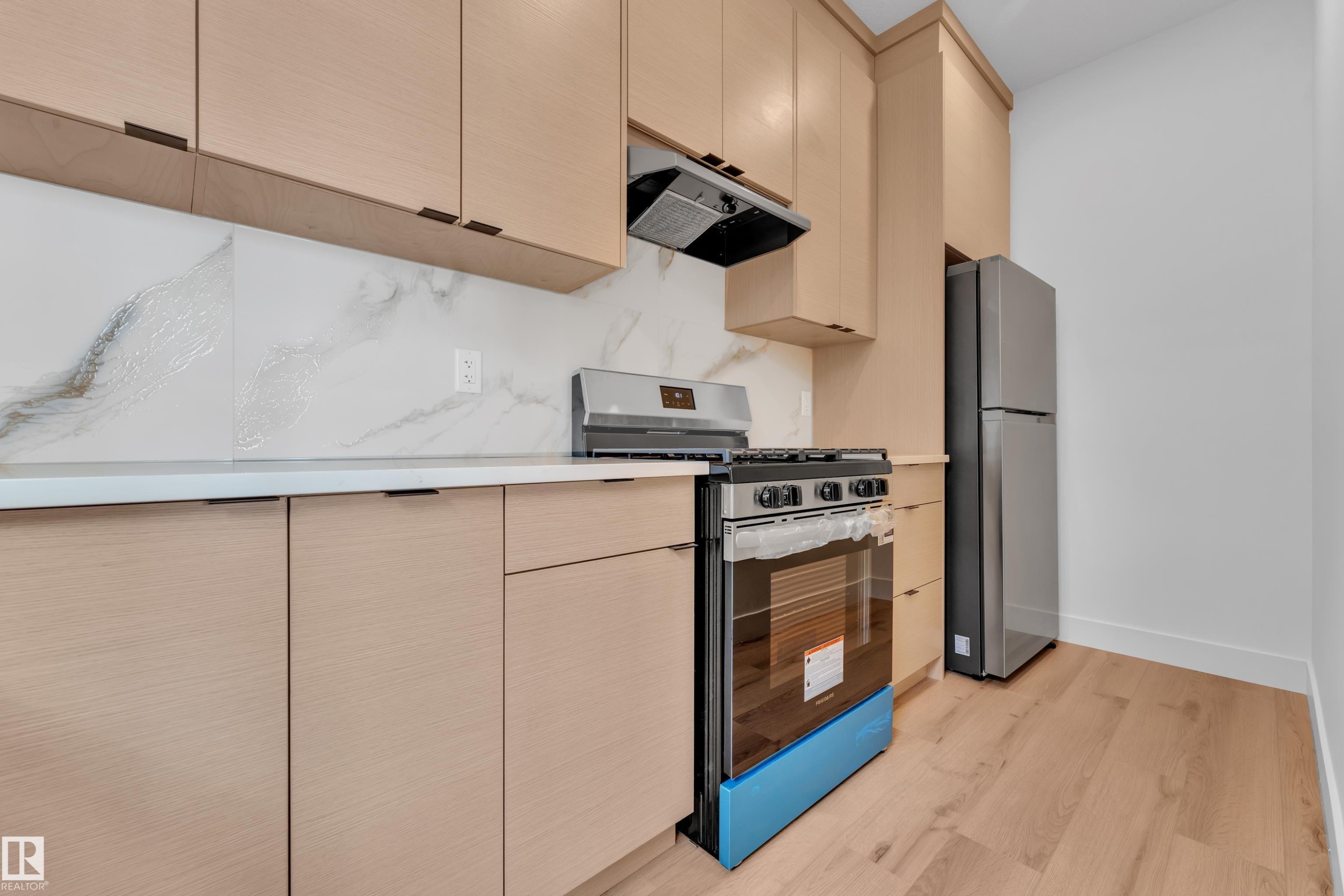 Kitchen featuring light-toned cabinetry, light countertops, and a white and gray veined backsplash - 503 Creekside Bay, Leduc, AB - Indoor Photo Showing Kitchen