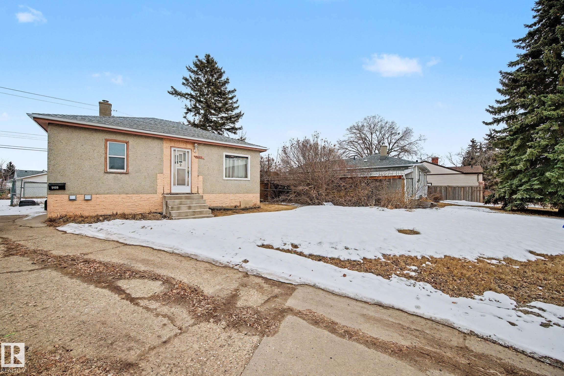 The property features a stucco exterior with a brick foundation, a front entrance with steps, and a driveway - 9409 154 Street, Edmonton, AB - Outdoor