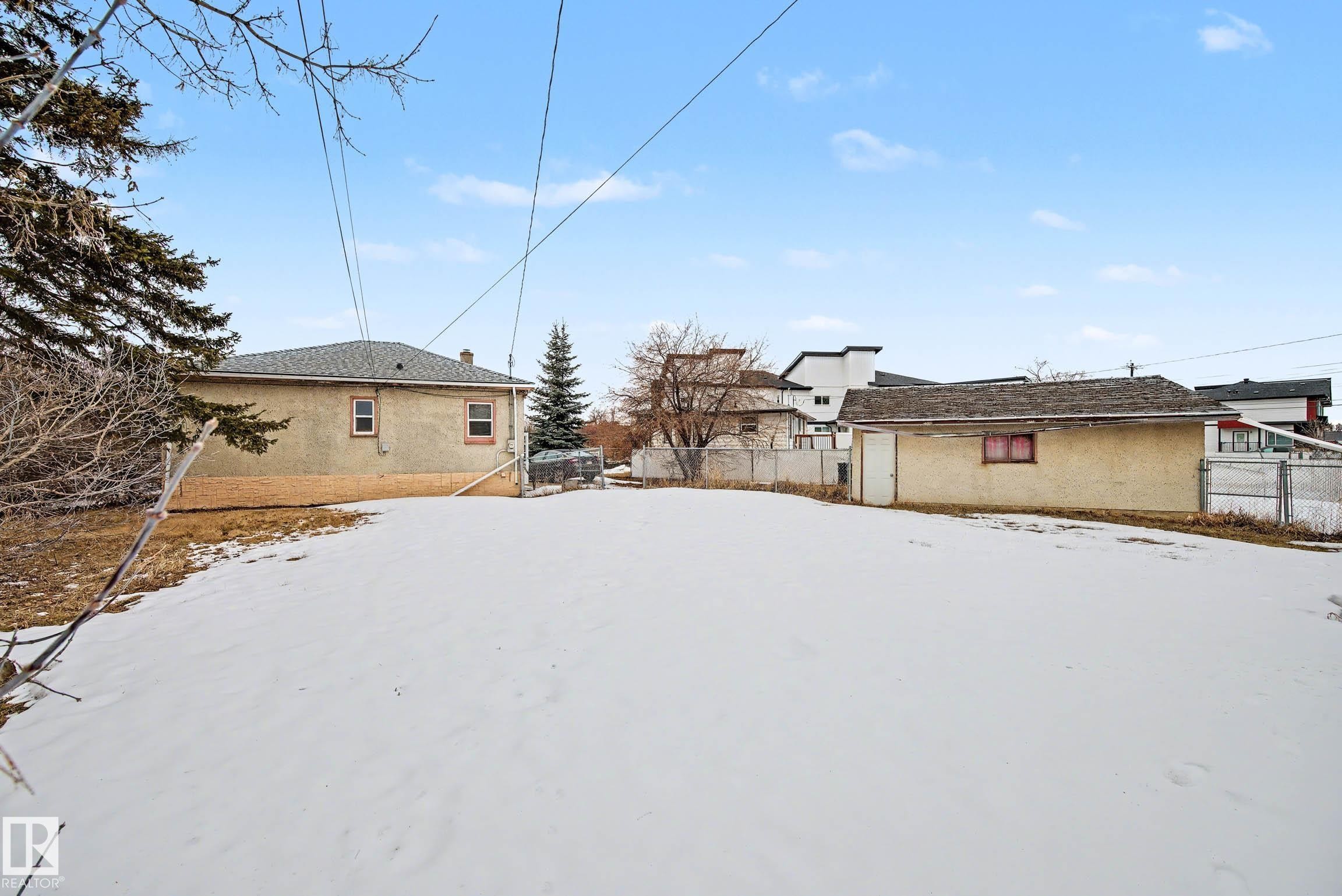 The property features an expansive yard with a snow-covered lawn, a detached garage, and a fenced perimeter - 9409 154 Street, Edmonton, AB - Outdoor