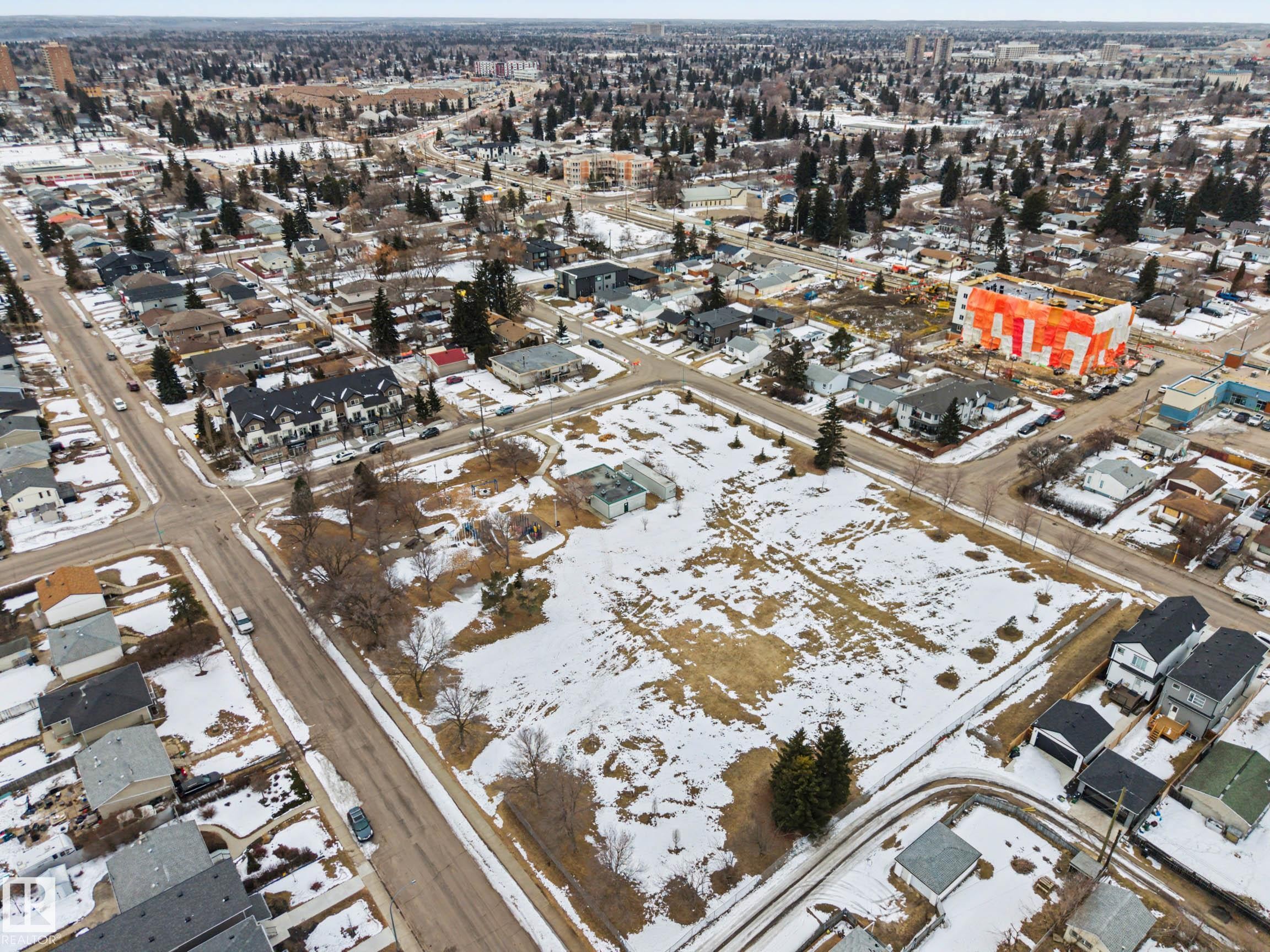 Expansive undeveloped land parcel surrounded by residential properties, featuring scattered trees and a partial covering of snow - 9409 154 Street, Edmonton, AB - With View