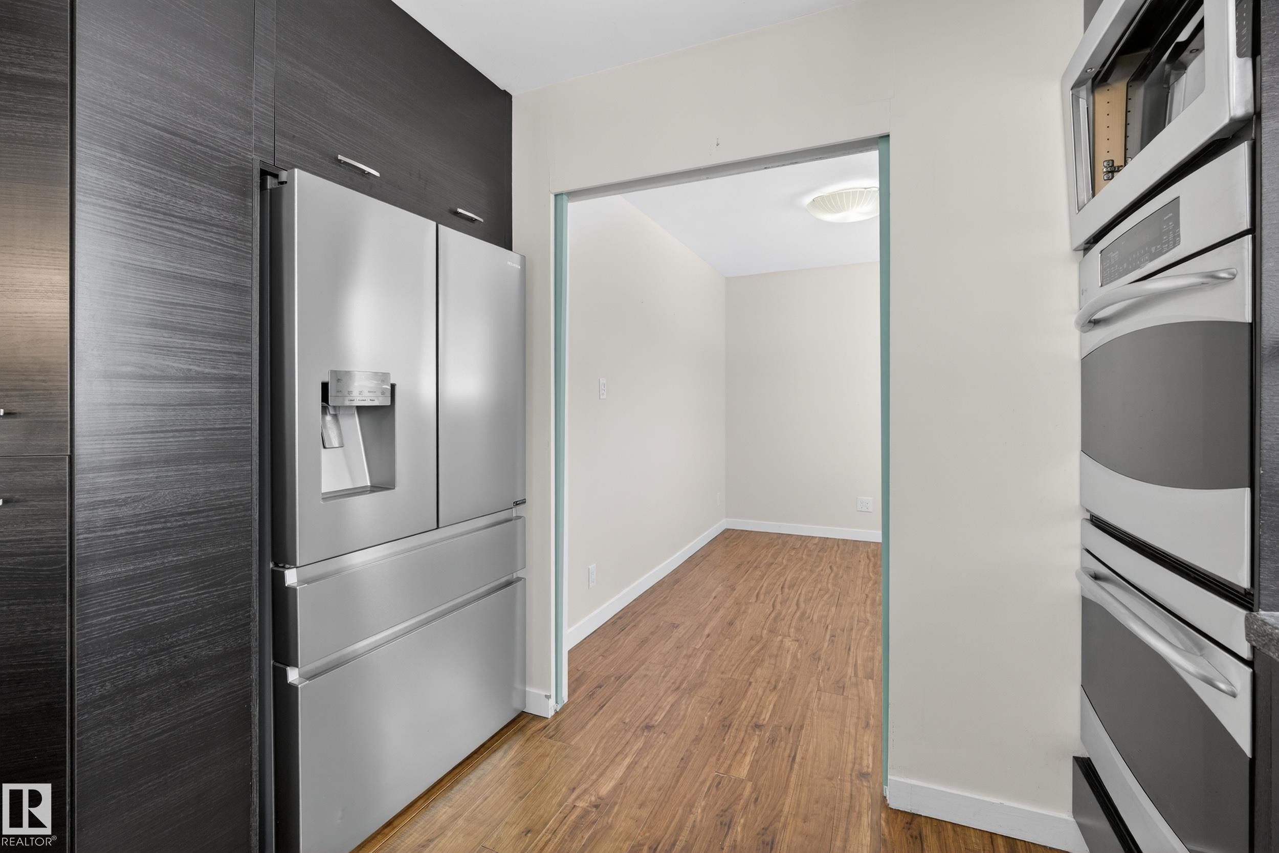 The kitchen features a stainless steel refrigerator with an external water/ice dispenser, dark wood-grain cabinetry, and built-in stainless steel double ovens - 3613 113 Avenue, Edmonton, AB - Indoor Photo Showing Kitchen