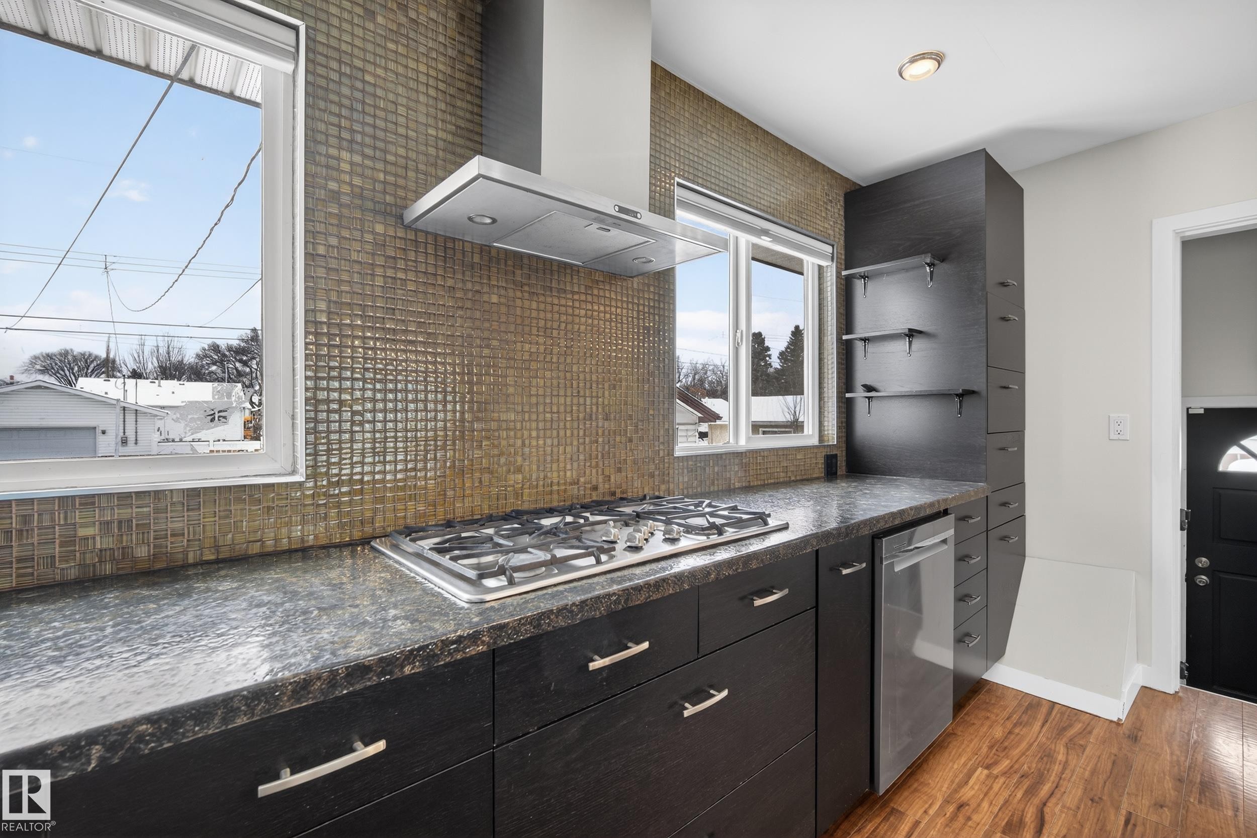 The kitchen features a stainless steel range hood, a gas cooktop, and dark cabinetry with silver hardware - 3613 113 Avenue, Edmonton, AB - Indoor Photo Showing Kitchen