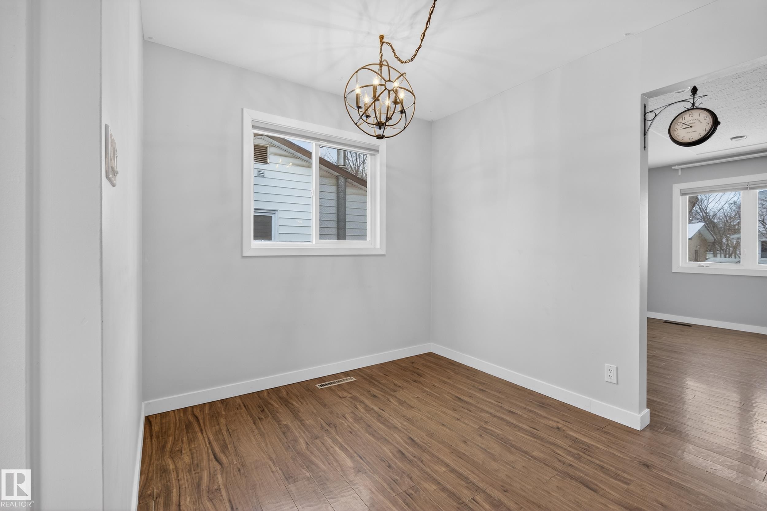 This room features hardwood floors, a window with white trim, and a decorative ceiling light fixture - 3613 113 Avenue, Edmonton, AB - Indoor Photo Showing Other Room