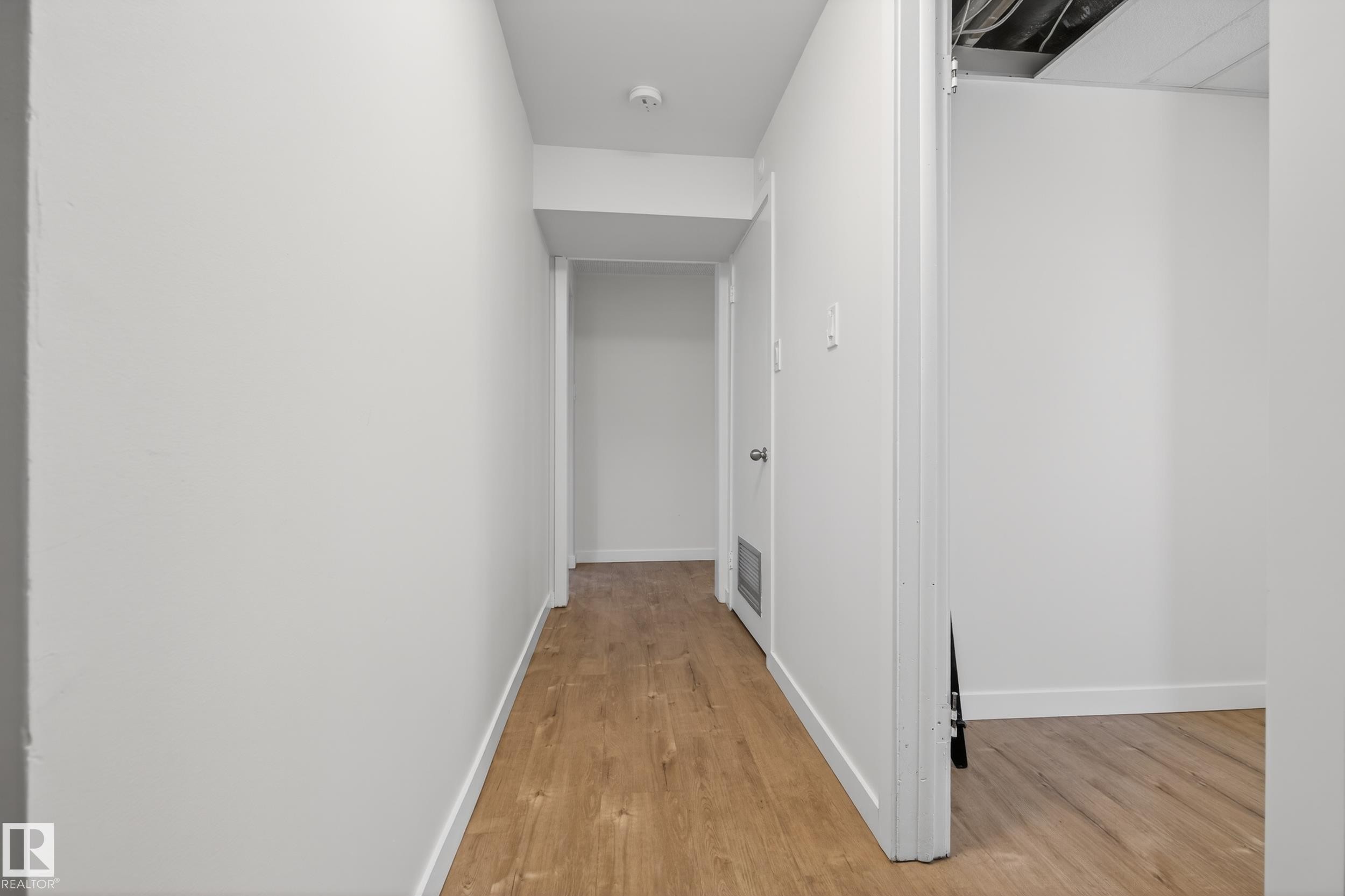 The property features a hallway with light wood flooring and white walls, leading to an open doorway - 3613 113 Avenue, Edmonton, AB - Indoor Photo Showing Other Room