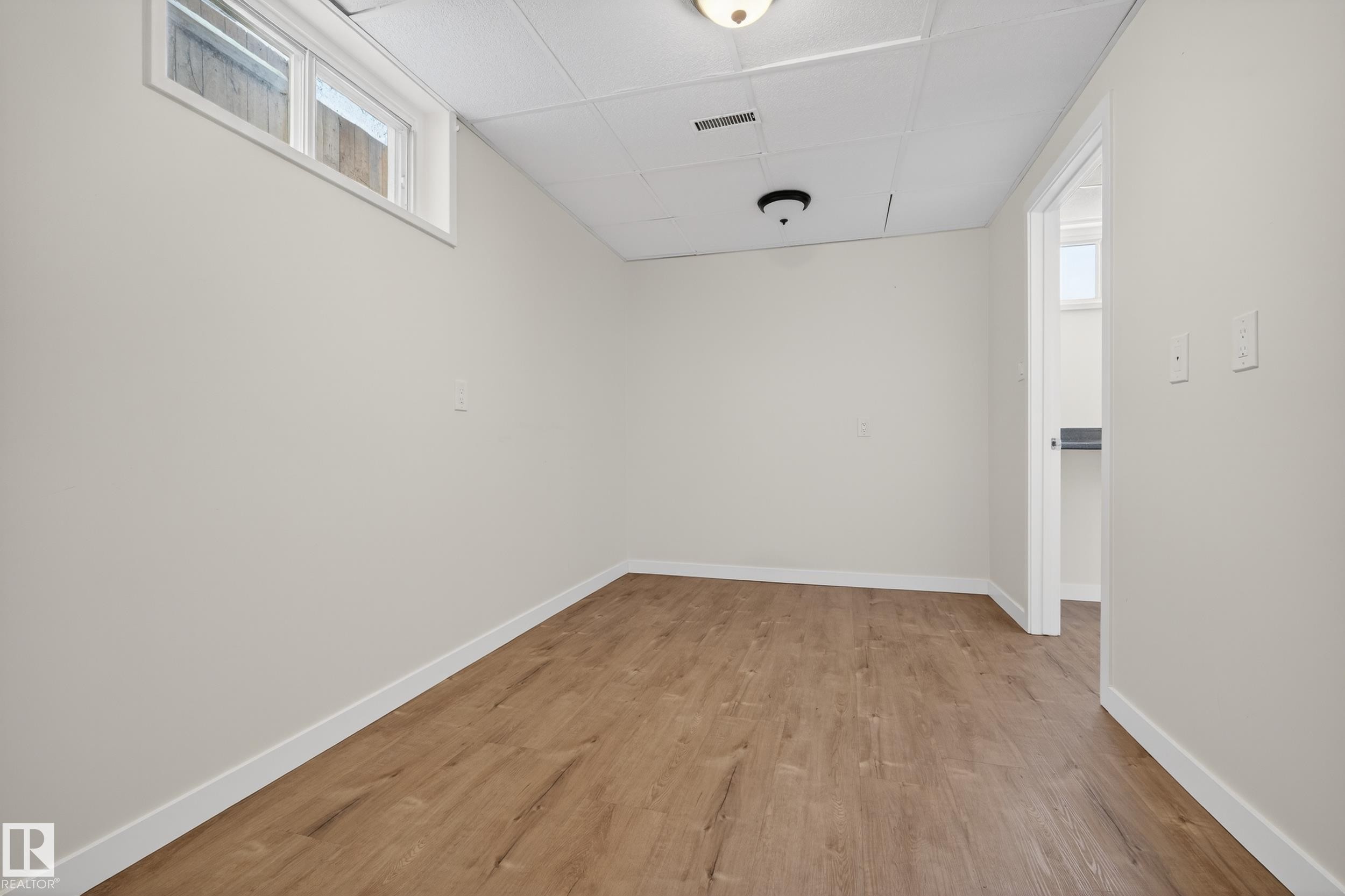 This room features light-toned walls, wood-look flooring, and a drop ceiling with recessed lighting - 3613 113 Avenue, Edmonton, AB - Indoor Photo Showing Other Room
