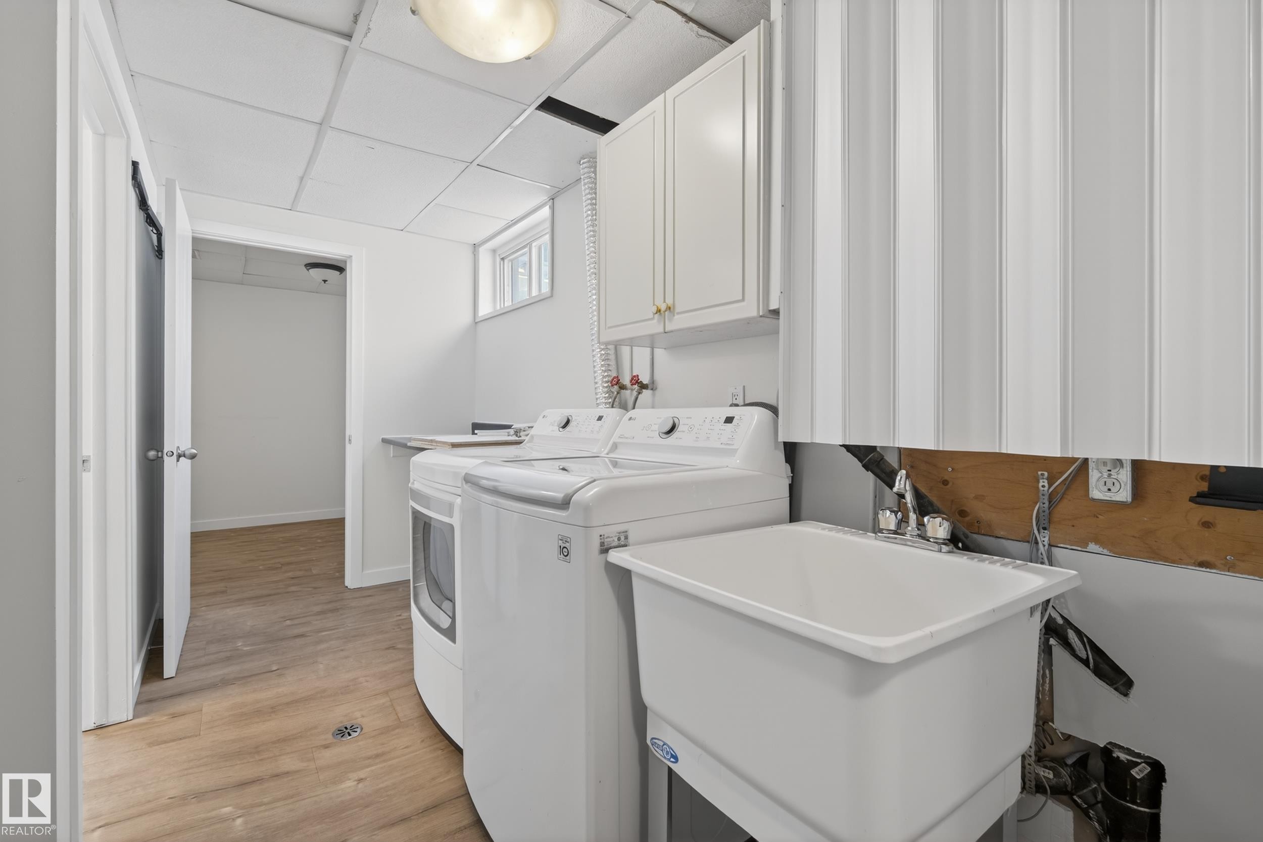 The laundry area features a utility sink, a window, and overhead cabinetry - 3613 113 Avenue, Edmonton, AB - Indoor Photo Showing Laundry Room
