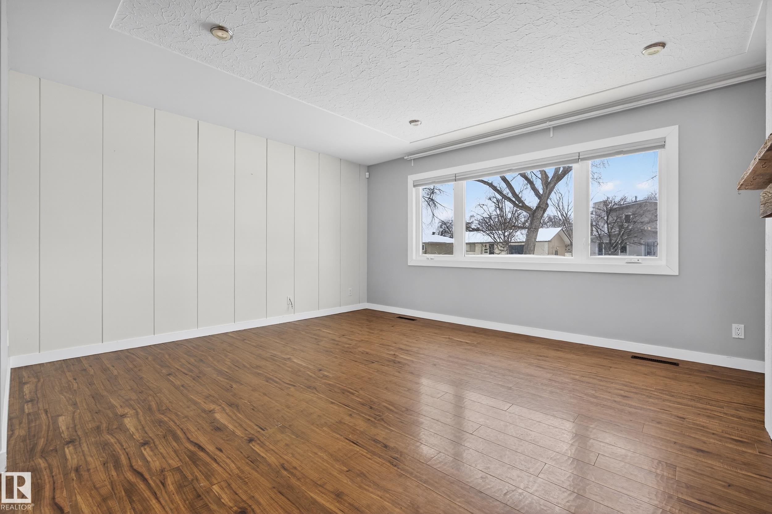 Spacious room featuring rich wood flooring, a large window providing ample natural light, and recessed ceiling lighting - 3613 113 Avenue, Edmonton, AB - Indoor Photo Showing Other Room