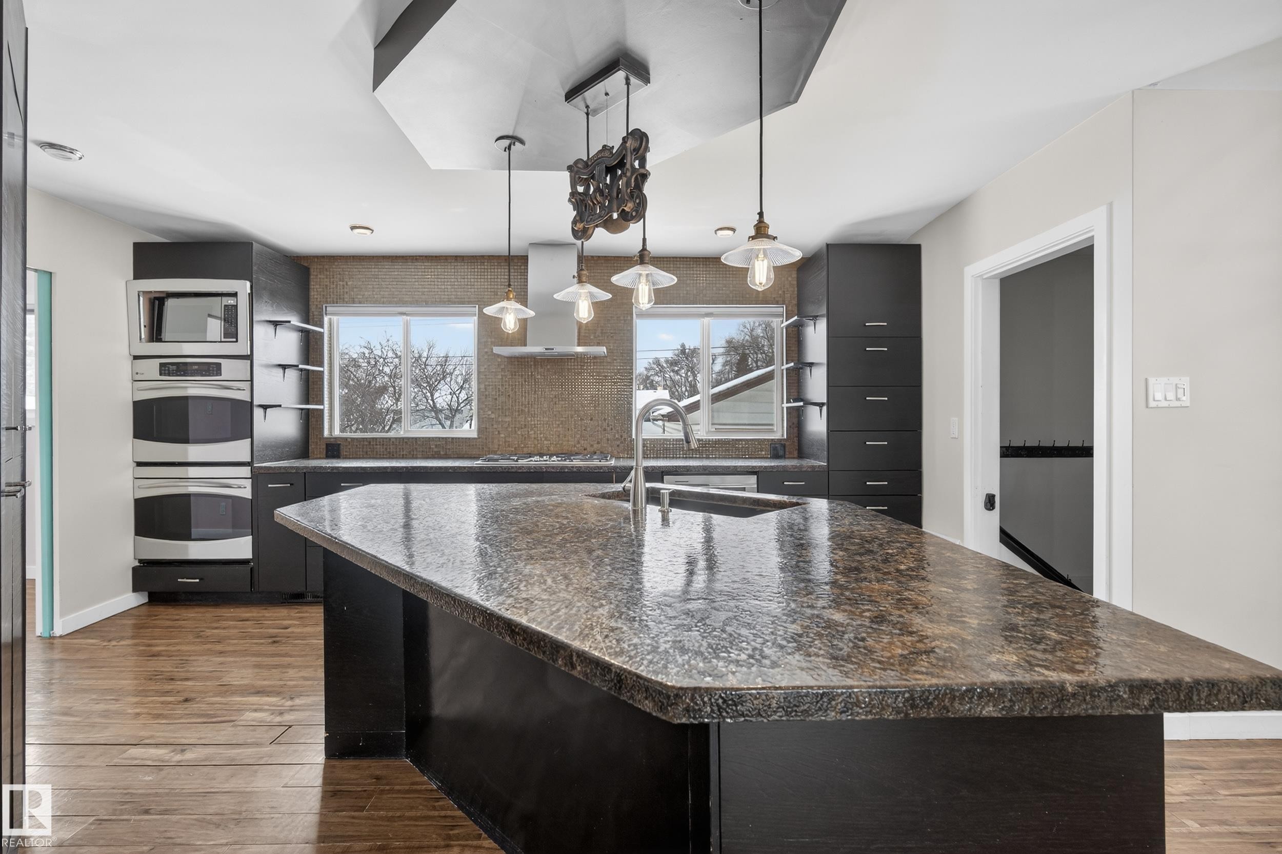 Kitchen featuring a large island with a speckled countertop, dark cabinetry, and hardwood floors - 3613 113 Avenue, Edmonton, AB - Indoor Photo Showing Kitchen With Upgraded Kitchen