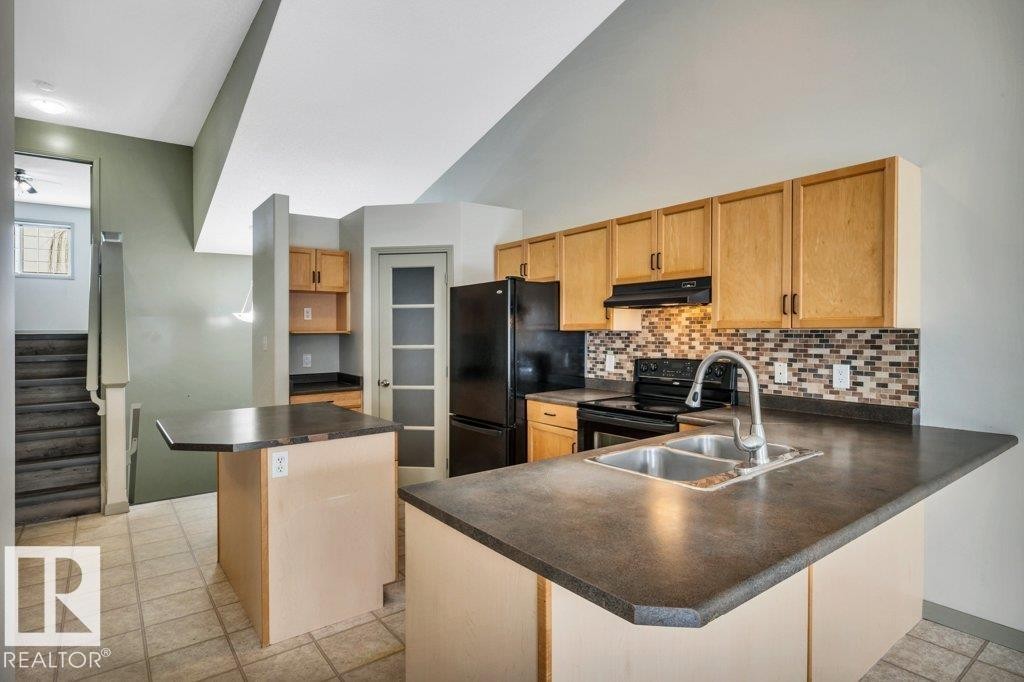 The kitchen features light wood cabinetry, a mosaic tile backsplash, and a double basin sink - 902 Graham Wynd, Edmonton, AB - Indoor Photo Showing Kitchen With Double Sink