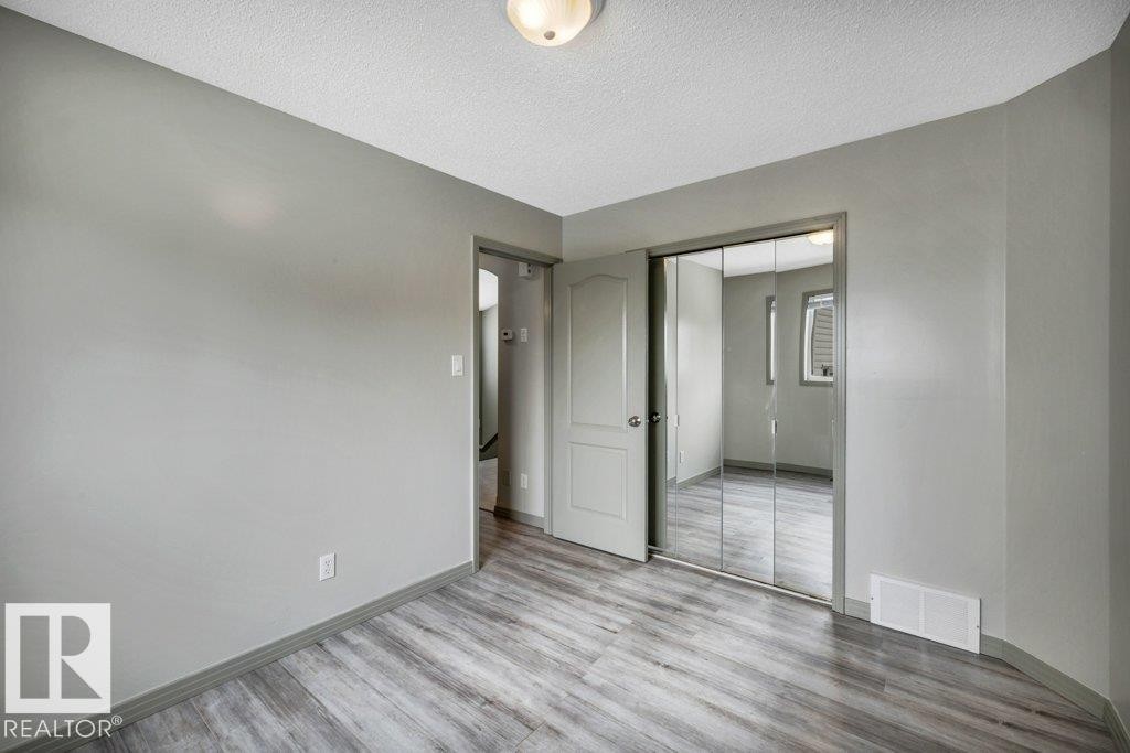 This room features a light gray color palette, wood-style flooring, and mirrored closet doors - 902 Graham Wynd, Edmonton, AB - Indoor Photo Showing Other Room