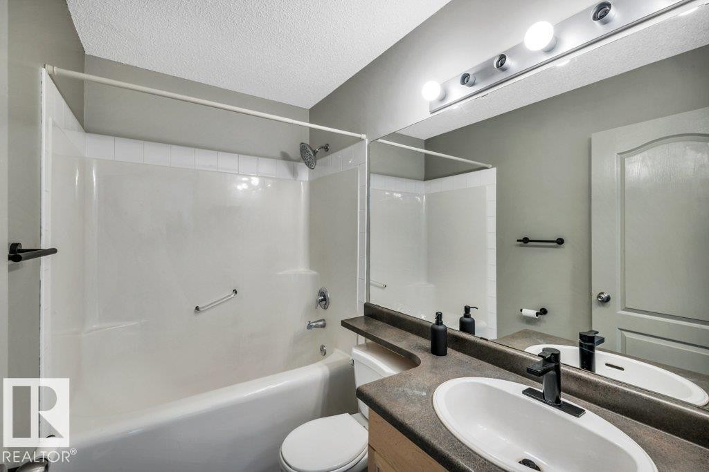 The bathroom features a vanity with an integrated sink and a large mirror - 902 Graham Wynd, Edmonton, AB - Indoor Photo Showing Bathroom