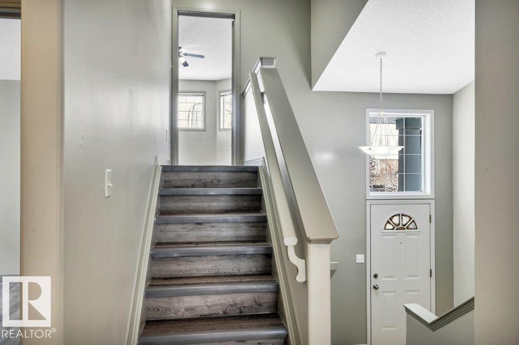 The property features a staircase with wood treads and light-toned risers, leading to a doorway - 902 Graham Wynd, Edmonton, AB - Indoor Photo Showing Other Room