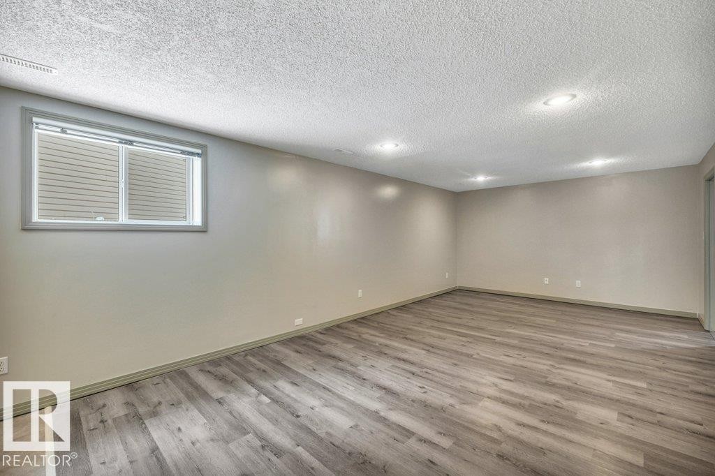 This spacious room features light-colored walls, recessed ceiling lighting, and a window with blinds - 902 Graham Wynd, Edmonton, AB - Indoor
