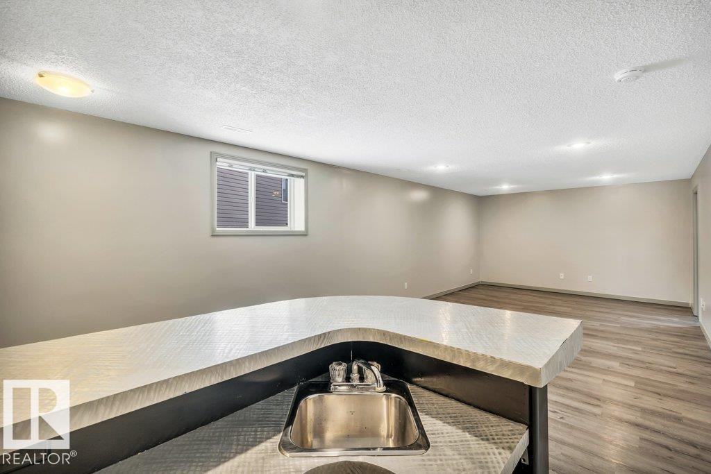 Spacious room featuring light-colored walls, recessed lighting, a window, and wood-look flooring - 902 Graham Wynd, Edmonton, AB - Indoor