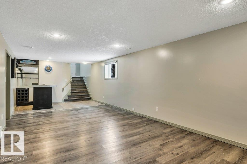 This spacious room features light-toned walls, recessed lighting, and durable wood-look flooring - 902 Graham Wynd, Edmonton, AB - Indoor Photo Showing Other Room