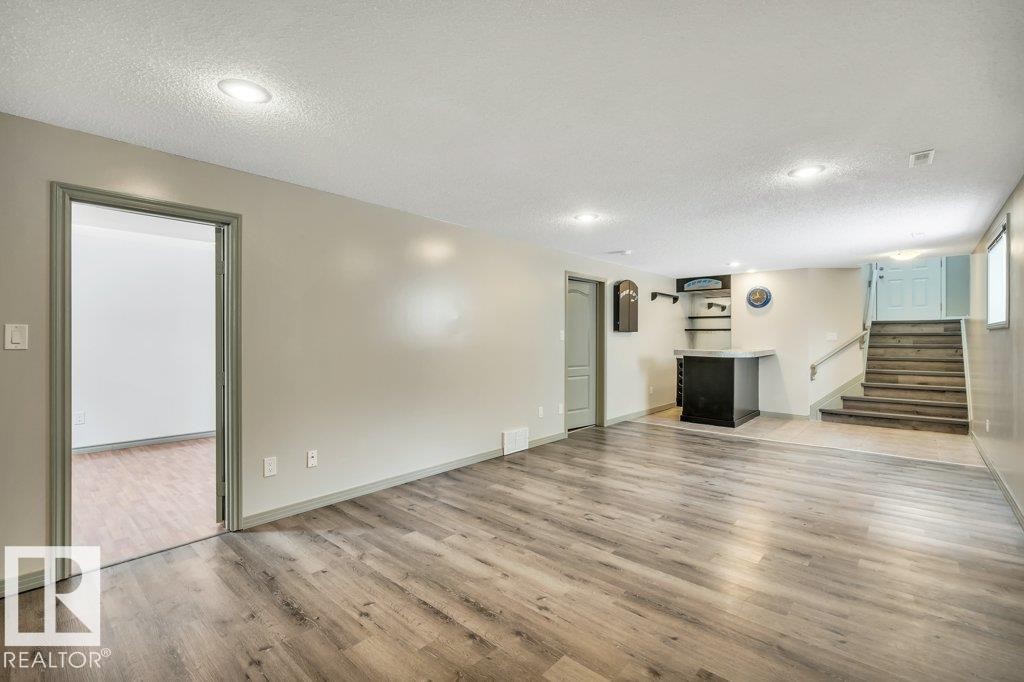 This spacious finished area features recessed lighting, durable wood-look flooring, and a built-in bar with shelving - 902 Graham Wynd, Edmonton, AB - Indoor