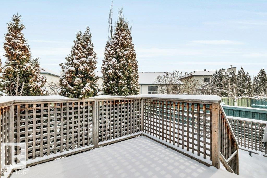 The property includes a wooden deck with a lattice railing, offering a view of surrounding mature evergreen trees - 902 Graham Wynd, Edmonton, AB - Outdoor