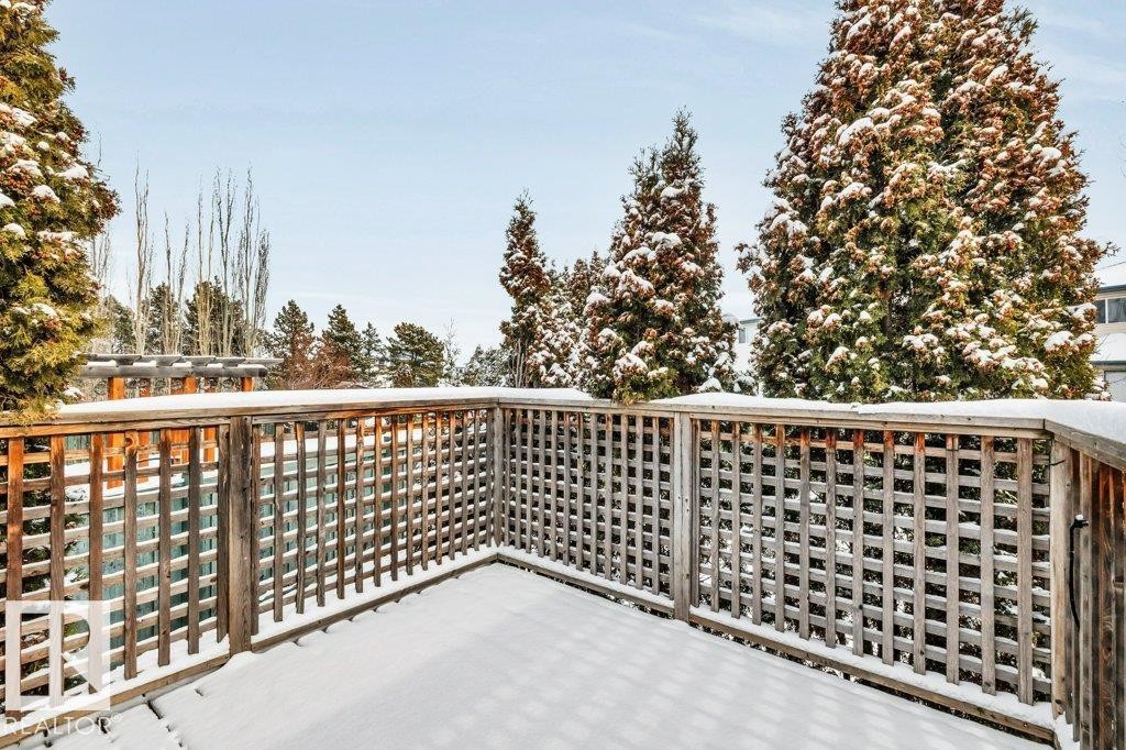 The property features a private outdoor deck with a wooden lattice railing, offering views of surrounding evergreen trees - 902 Graham Wynd, Edmonton, AB - Outdoor