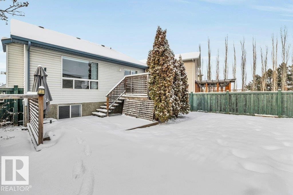 The property features a spacious rear yard with a wooden fence and mature evergreen trees - 902 Graham Wynd, Edmonton, AB - Outdoor
