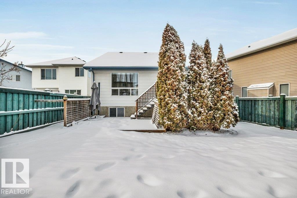 The property features a fenced yard with a patio area and mature evergreen trees - 902 Graham Wynd, Edmonton, AB - Outdoor