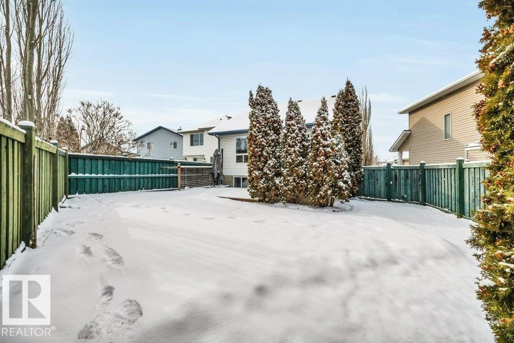 The property features a fenced yard with evergreen trees and a snow-covered lawn - 902 Graham Wynd, Edmonton, AB - Outdoor