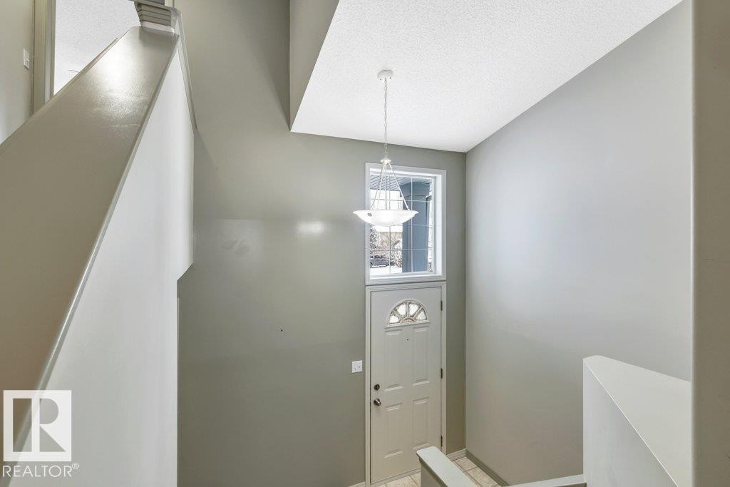 Entryway featuring a front door with a decorative glass insert, an overhead window, and a hanging light fixture - 902 Graham Wynd, Edmonton, AB - Indoor Photo Showing Other Room
