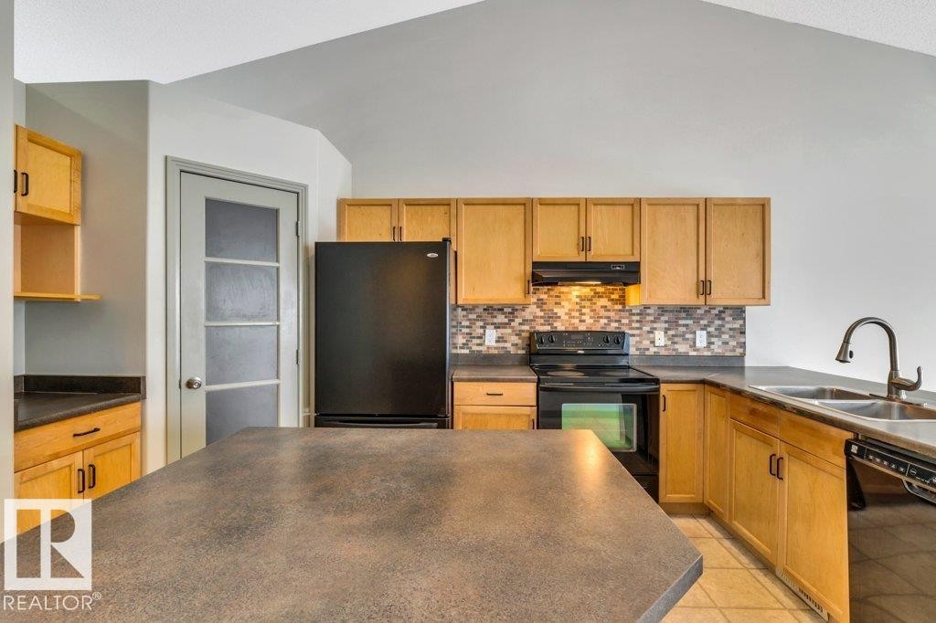 Kitchen featuring a black refrigerator, black range, and a double basin sink with a high-arc faucet - 902 Graham Wynd, Edmonton, AB - Indoor Photo Showing Kitchen With Double Sink