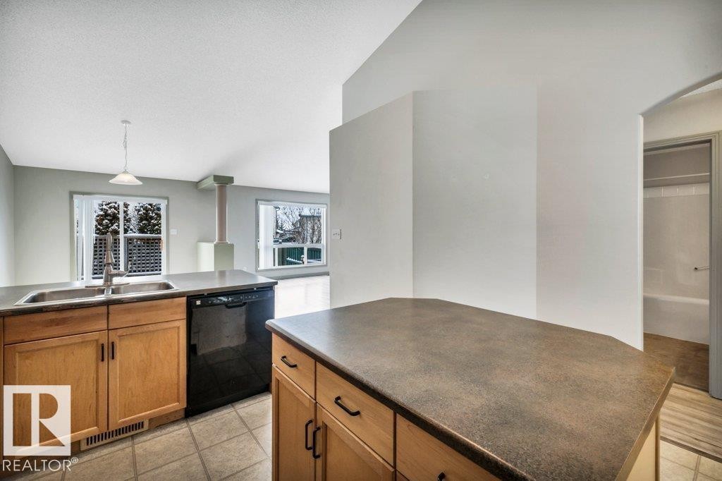 The kitchen features wood cabinetry, a double basin sink, and a black dishwasher - 902 Graham Wynd, Edmonton, AB - Indoor Photo Showing Kitchen With Double Sink