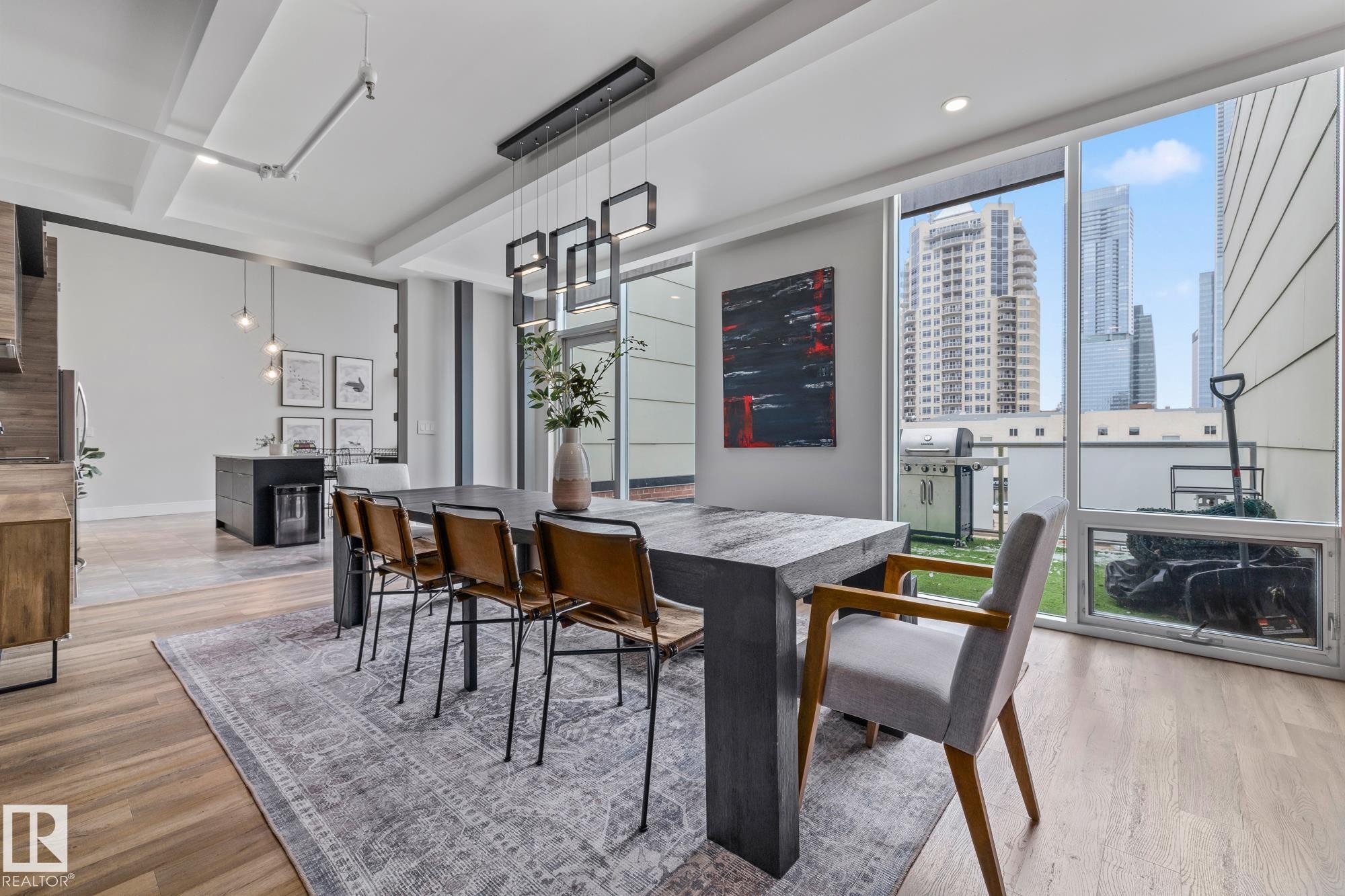 The property features an open-concept living area with hardwood floors, a modern chandelier, and floor-to-ceiling windows - 314 10309 107 Street, Edmonton, AB -