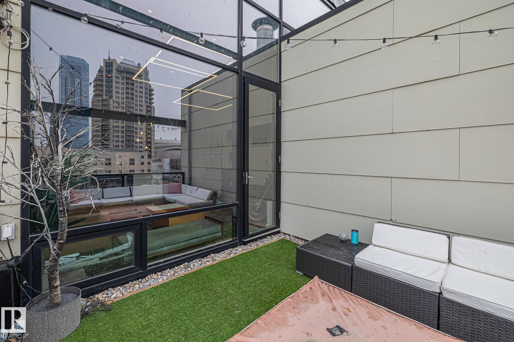 This property features an exterior terrace with artificial turf and decorative string lights - 314 10309 107 Street, Edmonton, AB - With Exterior