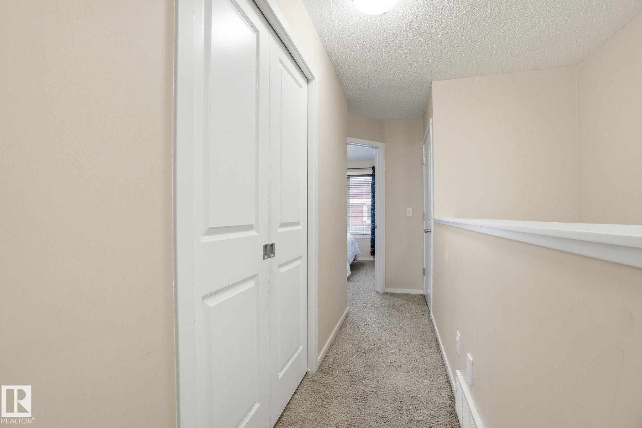 Hallway featuring light-colored walls, white trim, and carpeted flooring - 75 603 Watt Boulevard, Edmonton, AB - Indoor Photo Showing Other Room