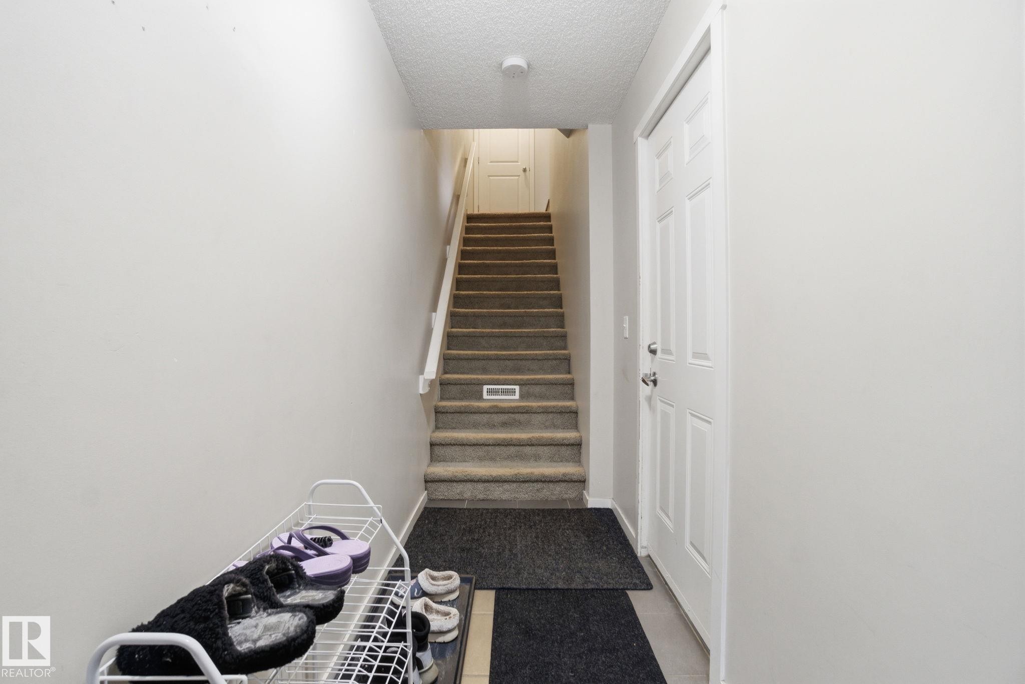 Entryway with light-colored walls, carpeted stairs, and a white paneled door - 75 603 Watt Boulevard, Edmonton, AB - Indoor Photo Showing Other Room
