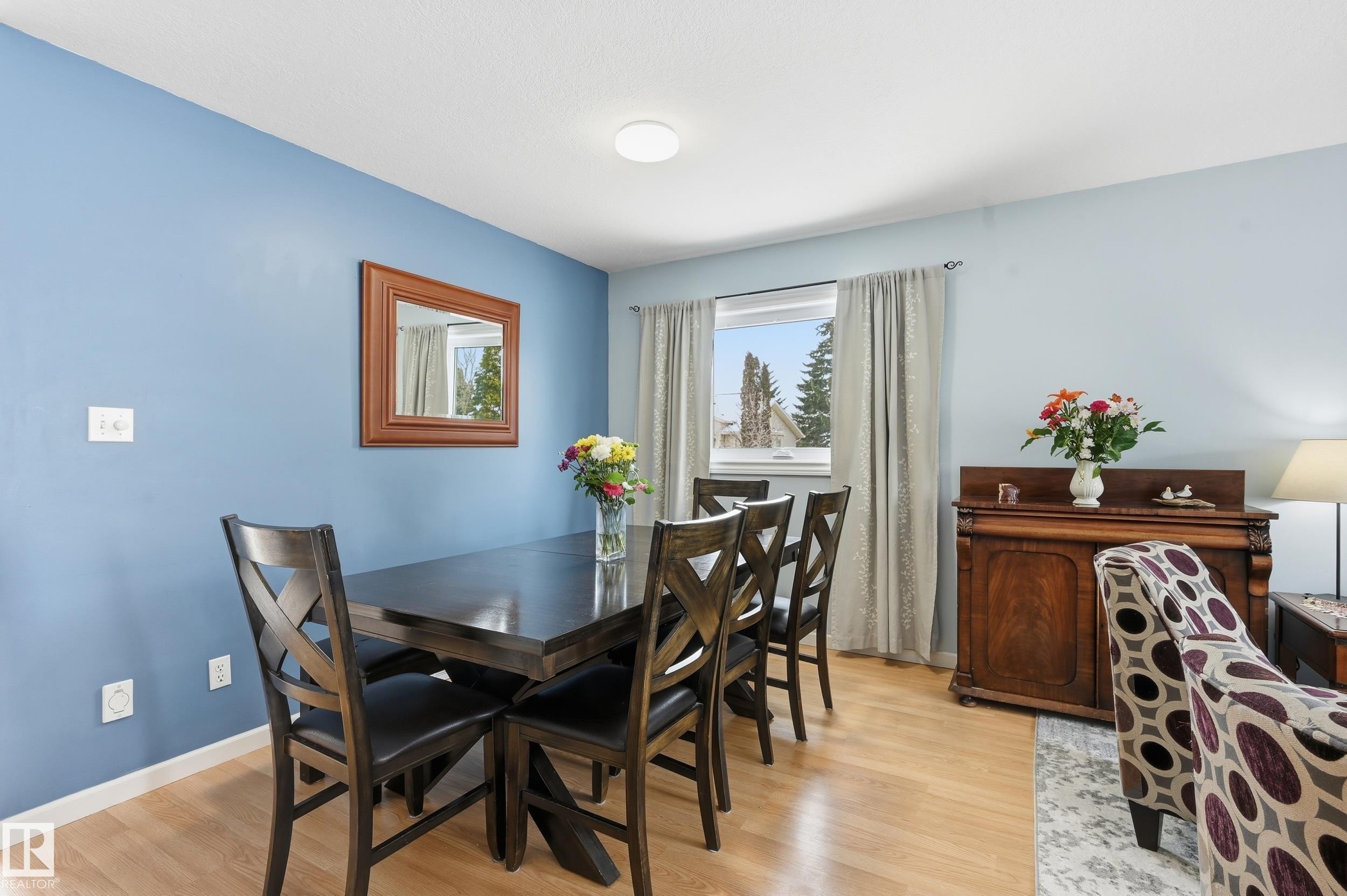 Dining area featuring hardwood style flooring, a window with curtains, and light blue walls - 85 Arlington Drive, St. Albert, AB - Indoor Photo Showing Dining Room