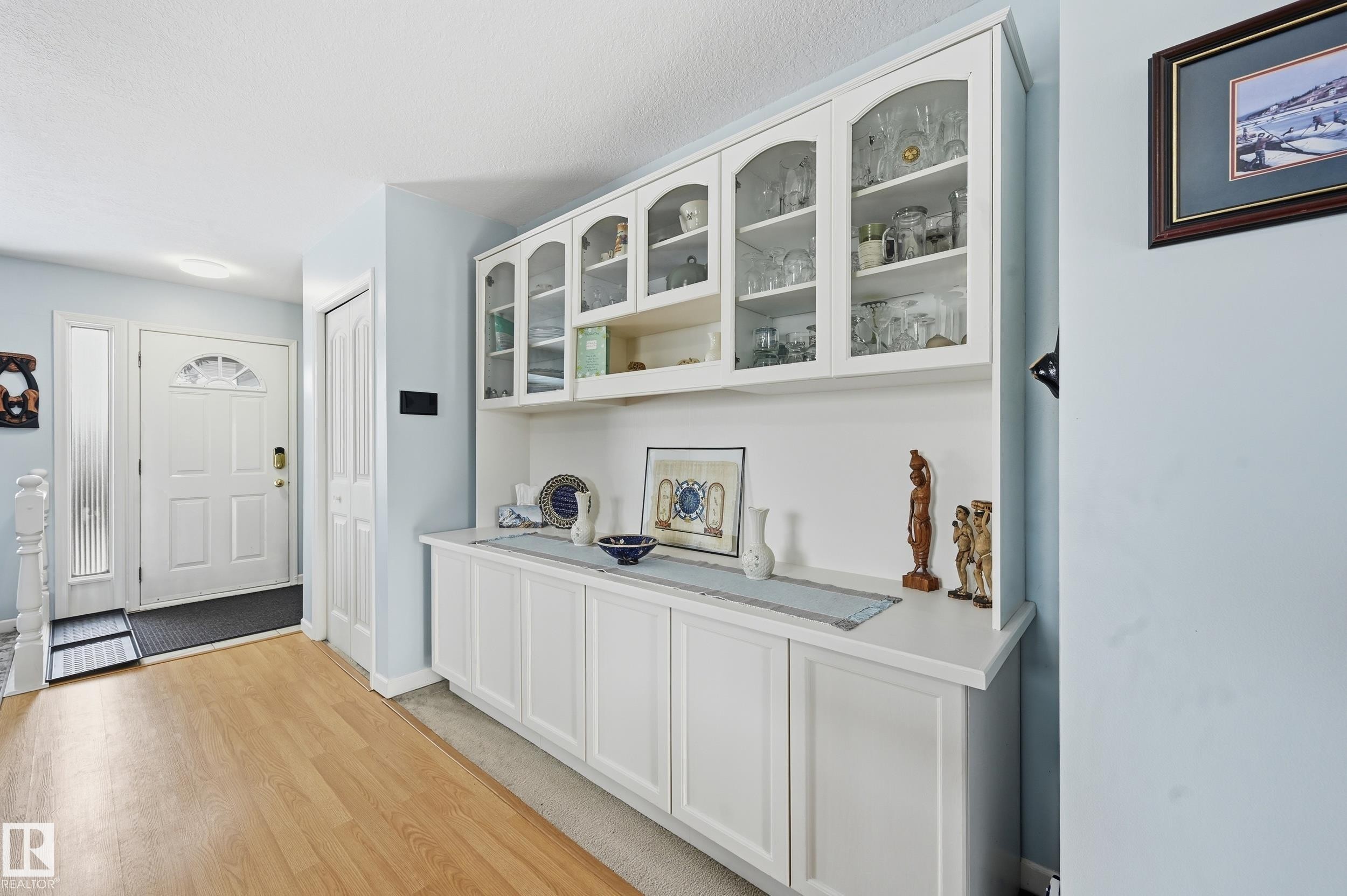 The entrance features a white paneled door with an arched glass insert and a sidelight, complemented by light wood flooring - 85 Arlington Drive, St. Albert, AB - Indoor Photo Showing Other Room