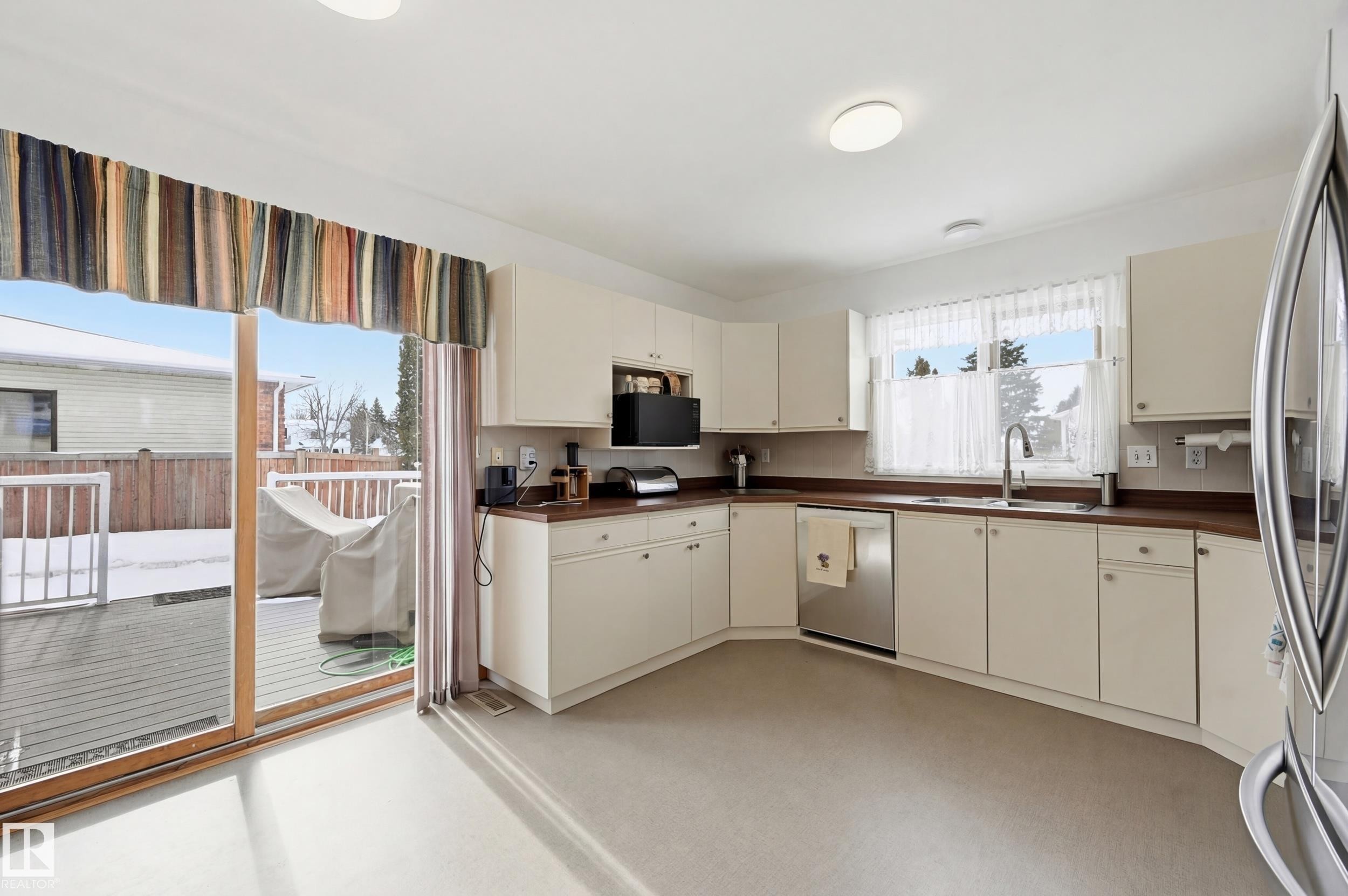 The kitchen features white cabinetry, a stainless steel dishwasher, and a window above the sink - 85 Arlington Drive, St. Albert, AB - Indoor Photo Showing Kitchen With Double Sink