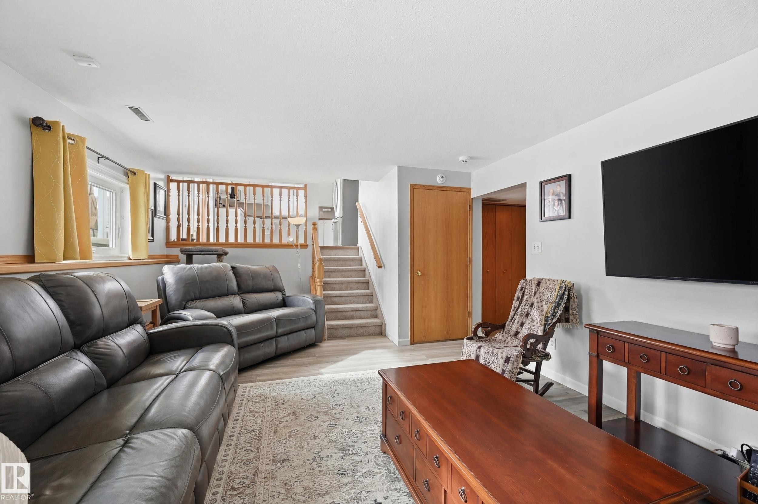 This versatile living area features light-colored walls, a window with yellow curtains, and durable flooring, providing a neutral backdrop for various design preferences - 85 Arlington Drive, St. Albert, AB - Indoor Photo Showing Living Room