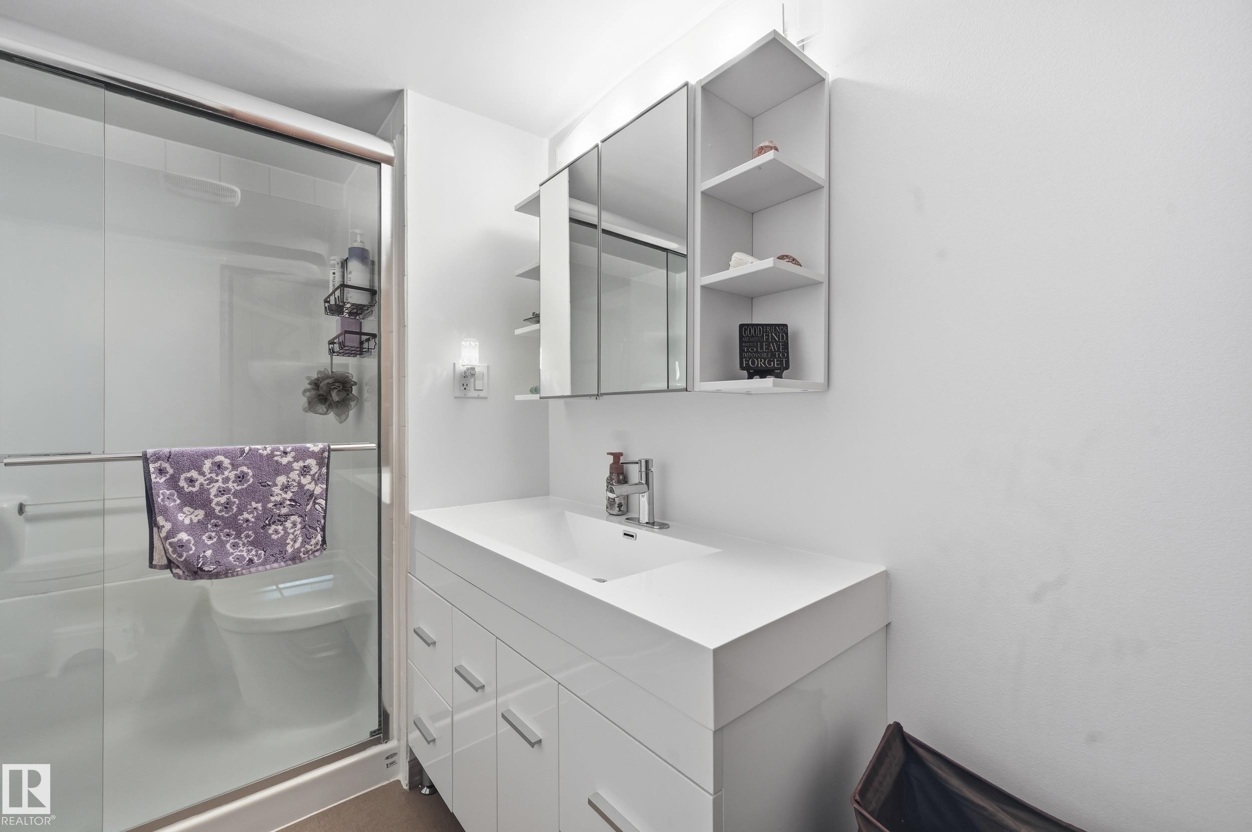 Bathroom featuring a white vanity with an integrated sink, a mirrored medicine cabinet, a shower with a sliding glass door, and an open shelving unit - 85 Arlington Drive, St. Albert, AB - Indoor Photo Showing Bathroom