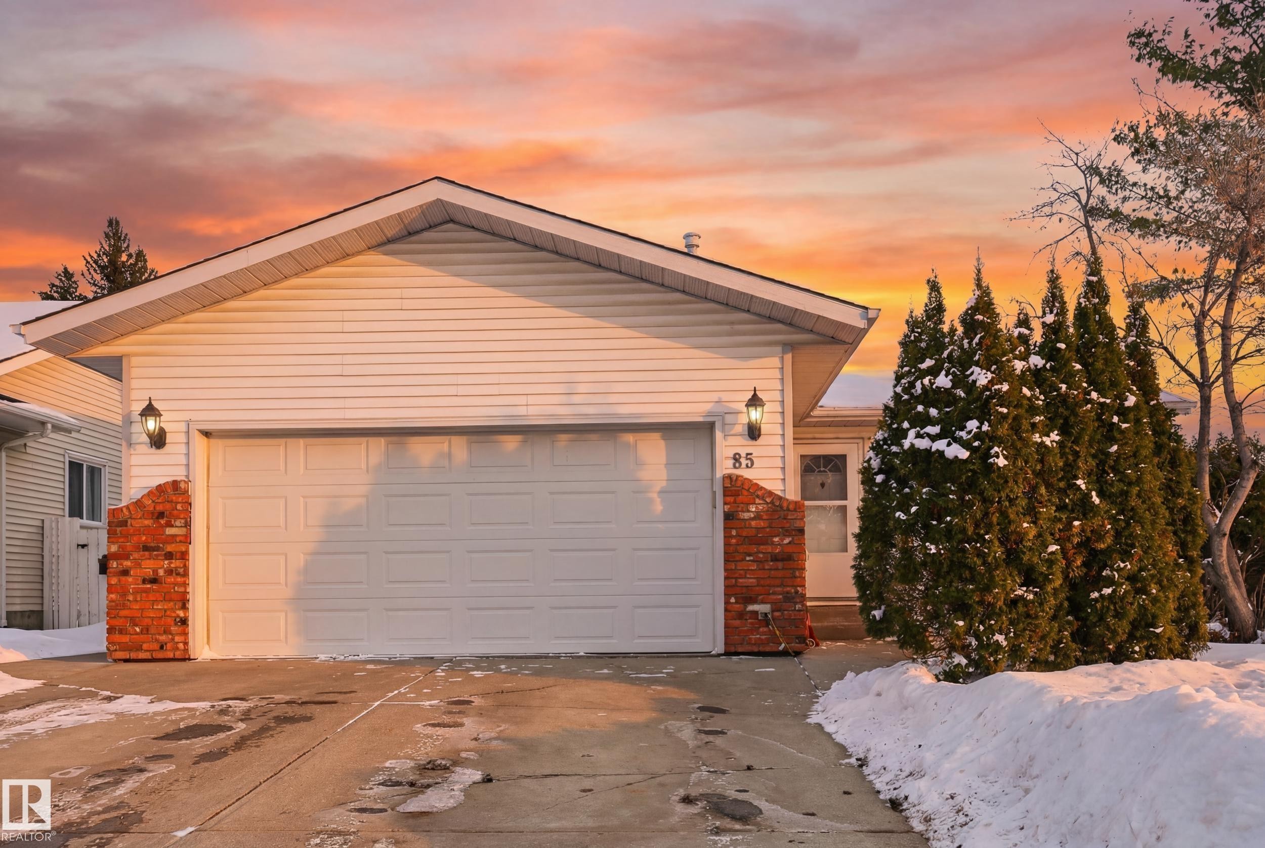 The property features a white exterior with brick accents, a two-car garage, and an inviting front entrance - 85 Arlington Drive, St. Albert, AB - Outdoor