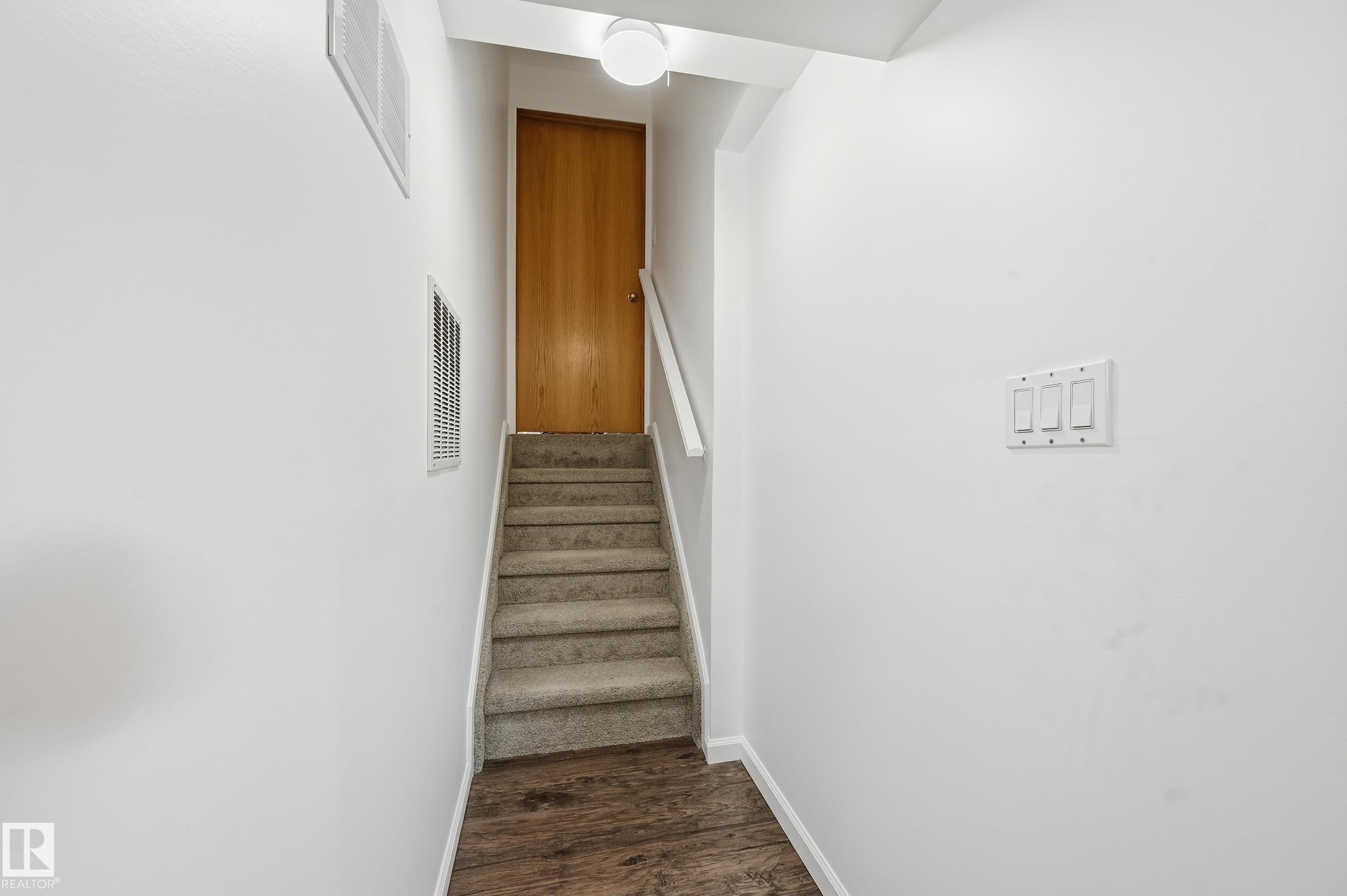 Staircase featuring carpeted steps and a light wood door at the landing - 85 Arlington Drive, St. Albert, AB - Indoor Photo Showing Other Room
