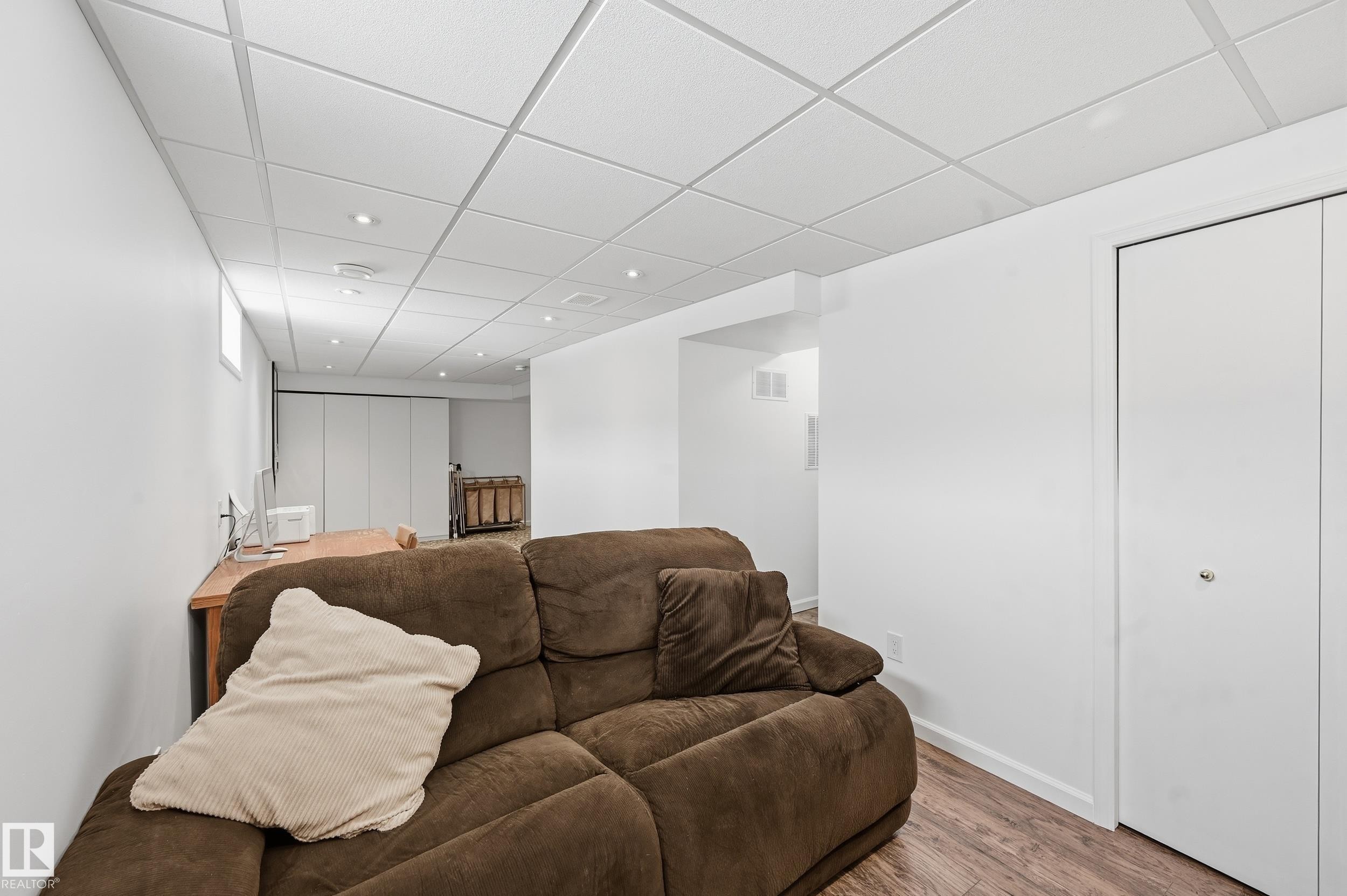 This spacious area features light wood-style flooring, white walls, and a drop ceiling with recessed lighting - 85 Arlington Drive, St. Albert, AB - Indoor