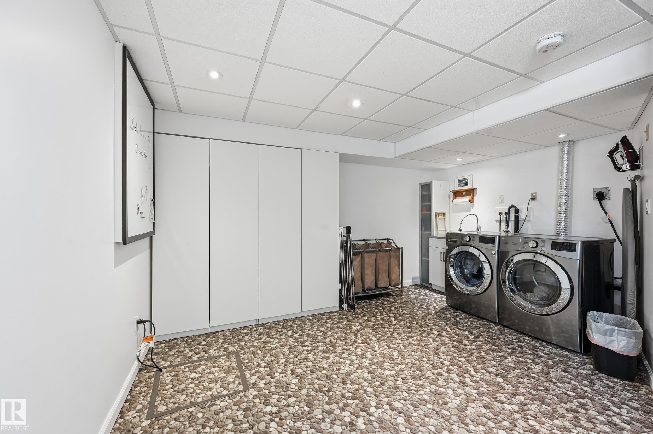 This utility room features modern pebble-style flooring, white walls, recessed ceiling lighting, and a white ceiling with a grid pattern - 85 Arlington Drive, St. Albert, AB - Indoor Photo Showing Laundry Room